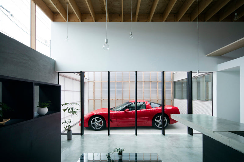 Red Corvette parked in garage visible from kitchen through a large glass retractable door.
