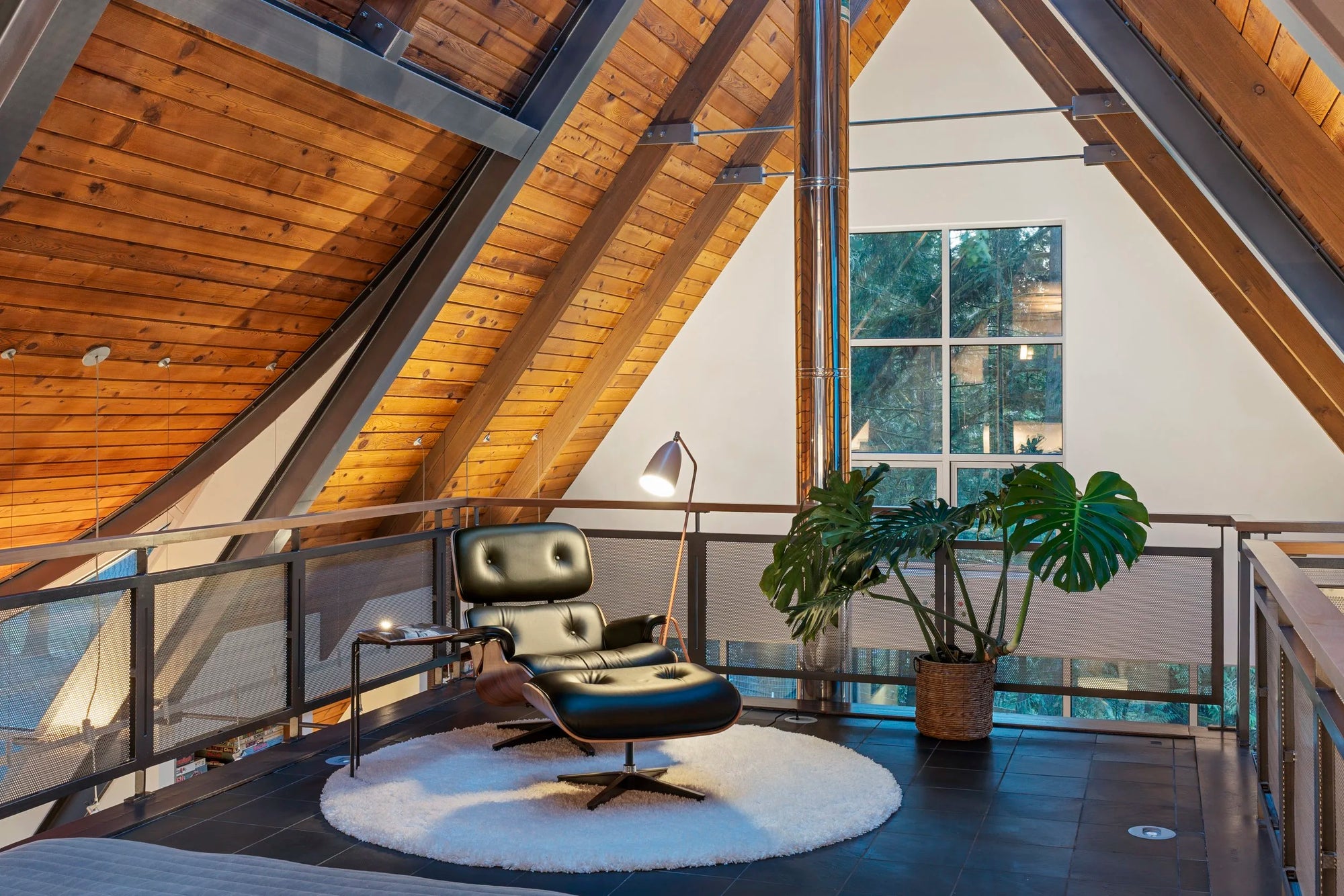 Modern interior with A-frame ceiling, Eames chair, and large window.