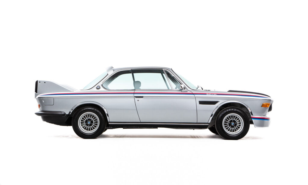 Side view of a classic silver 1973 BMW 3.2 CSL Batmobile with a white background