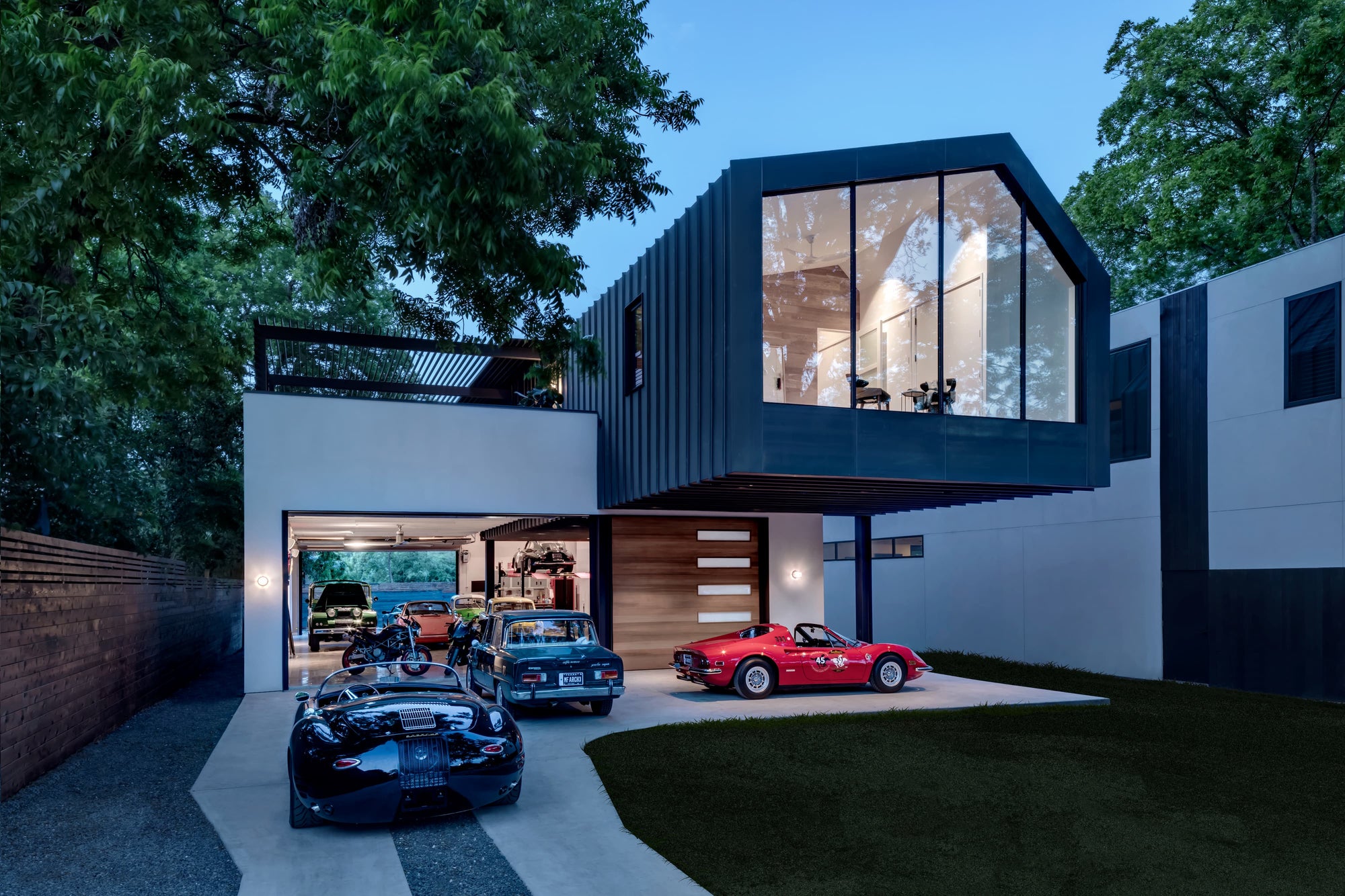 Modern Autohaus home in Austin, TX, showcasing a classic car collection in an illuminated garage.