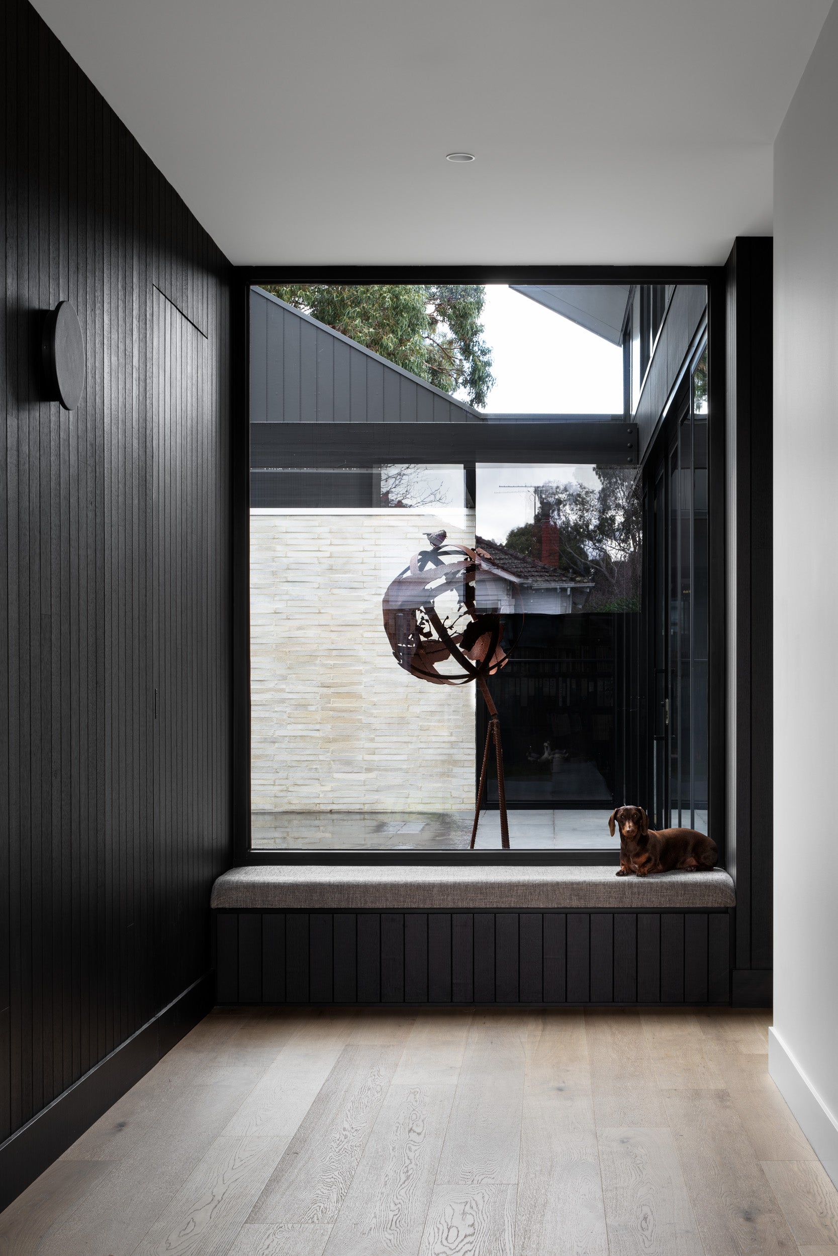 Entry hallway with dark-stained timber paneling and window seat at Campbell St House, Kew Melbourne