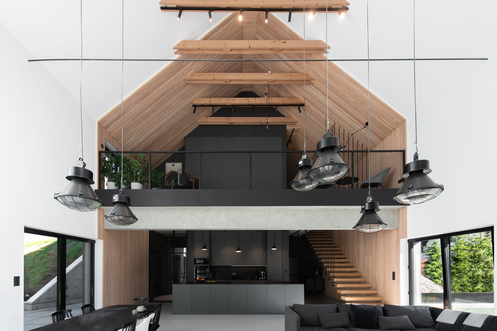 Double-height living space and kitchen with exposed wood ceiling and modern open-plan layout 