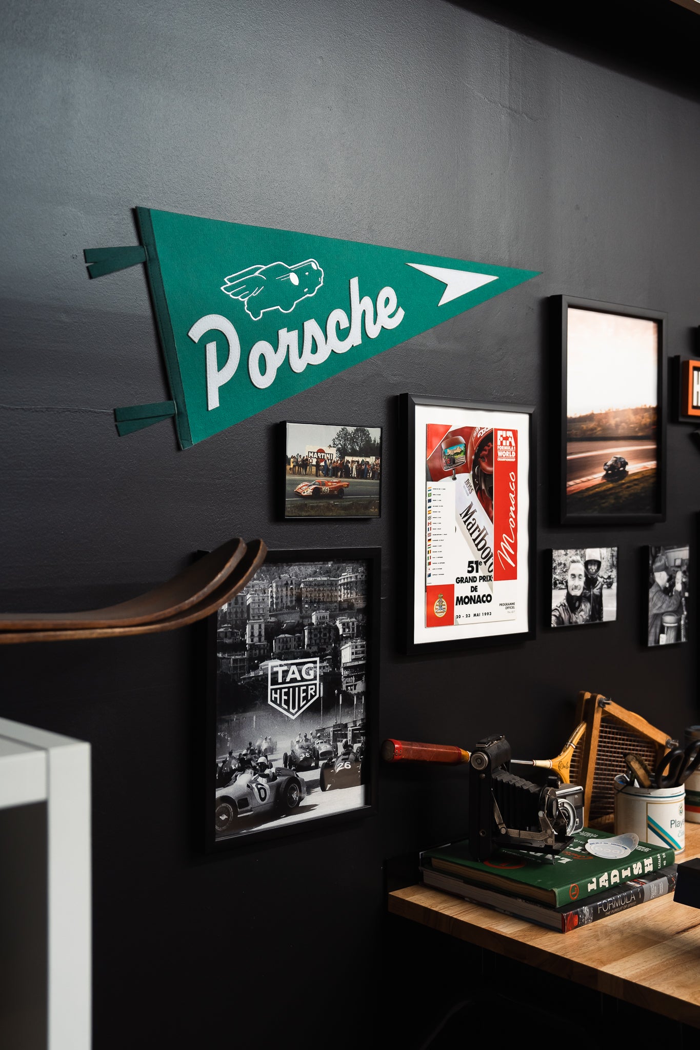 Garage workbench setup with Porsche wall banner, framed artwork, vintage memorabilia, tools, and soft ambient lighting