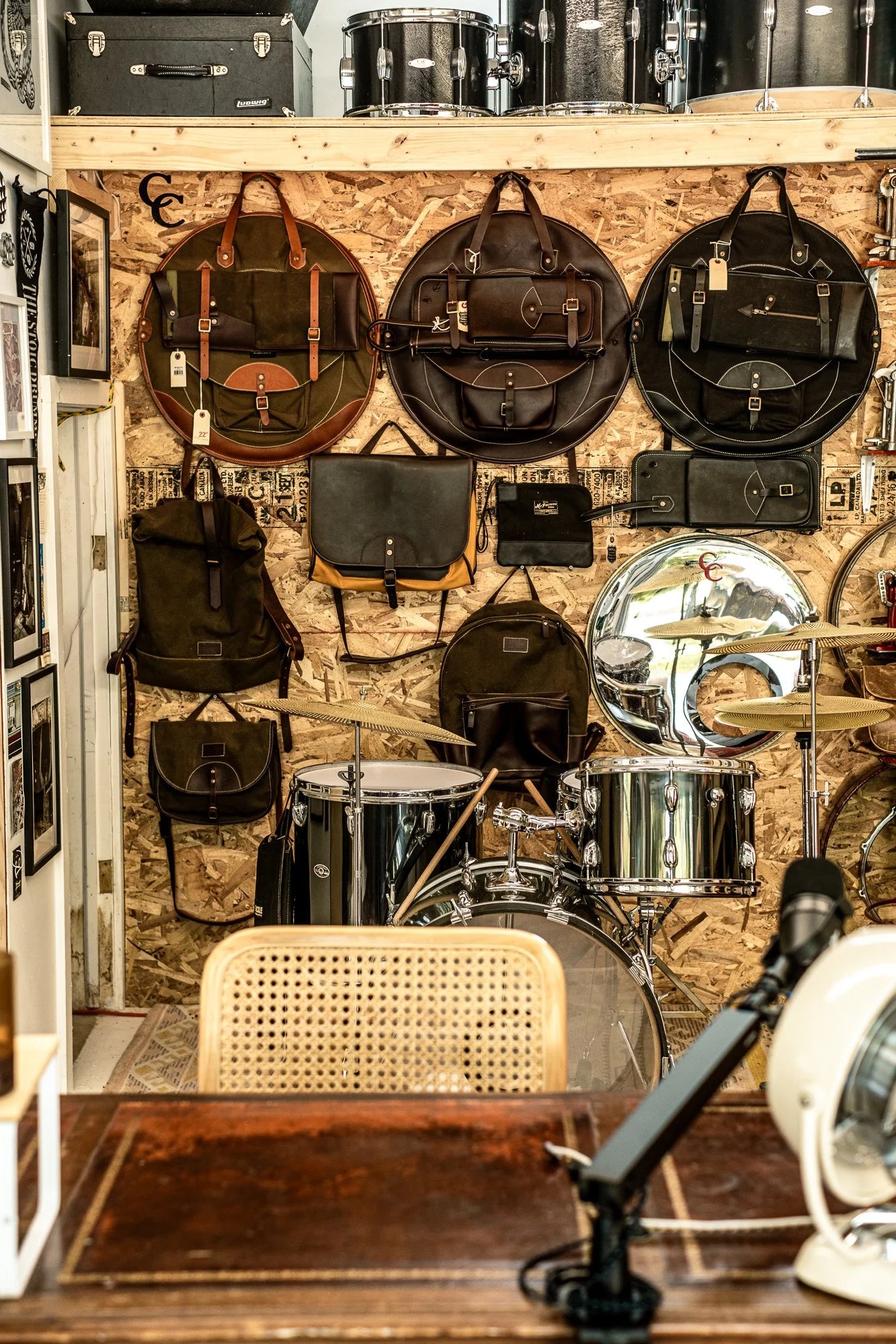 Drum set with various bags and equipment on a wooden wall in garage.