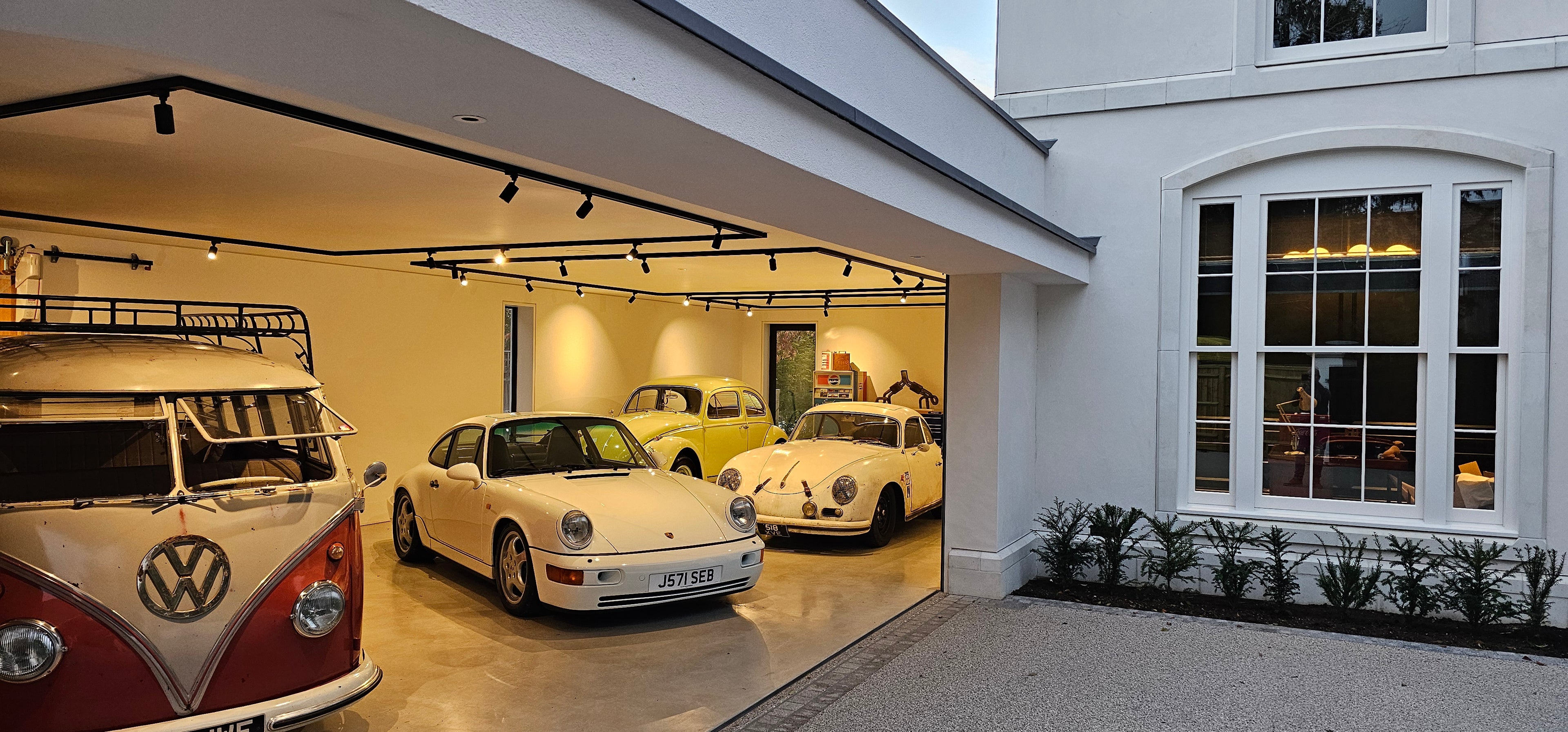Load video: Oak garage door on classic England home opening laterally to reveal classic Porsche and Volkswagen car collection.