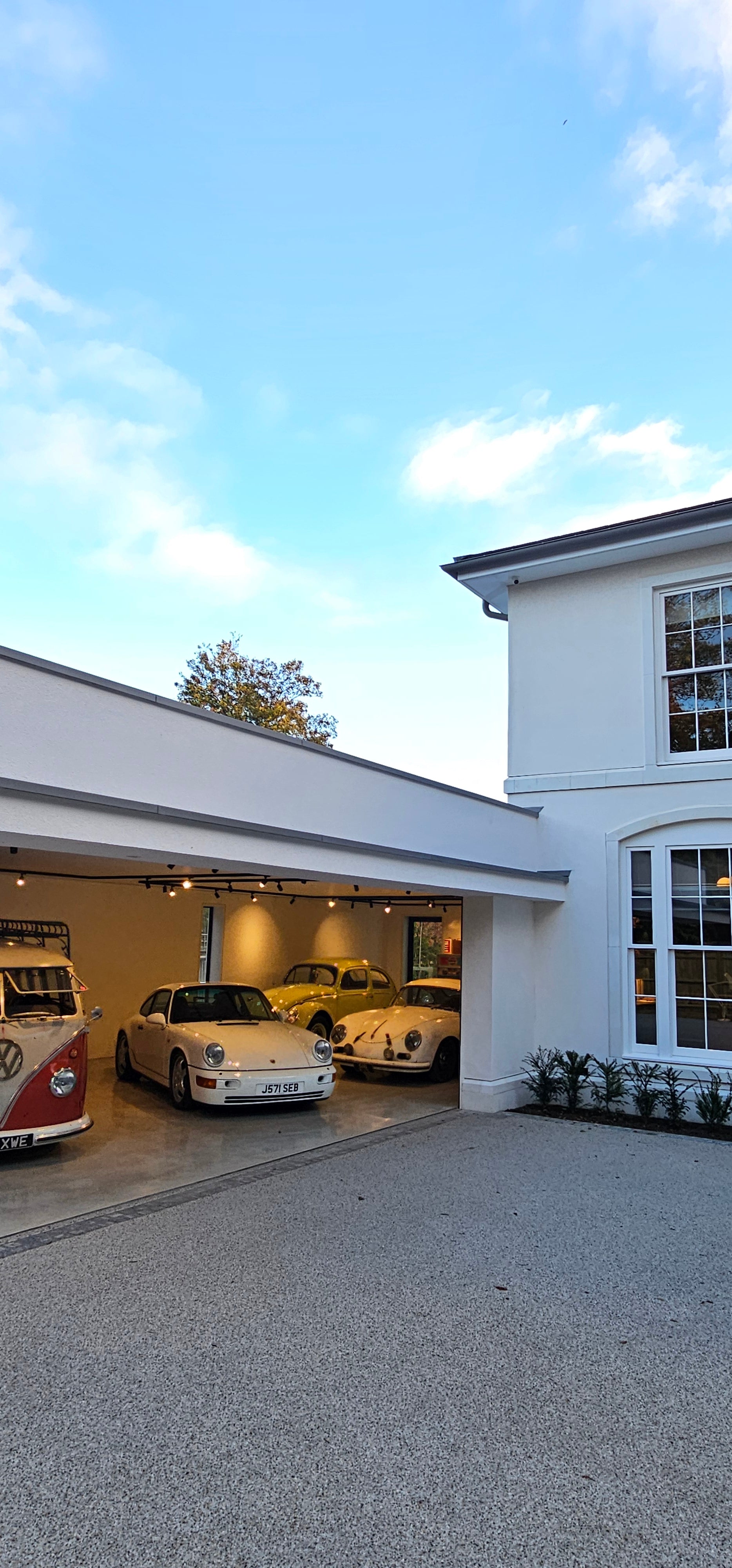 Gulbarg house by NEON Architecture with classic Porsche, VW Beetle, and VW van in garage display.