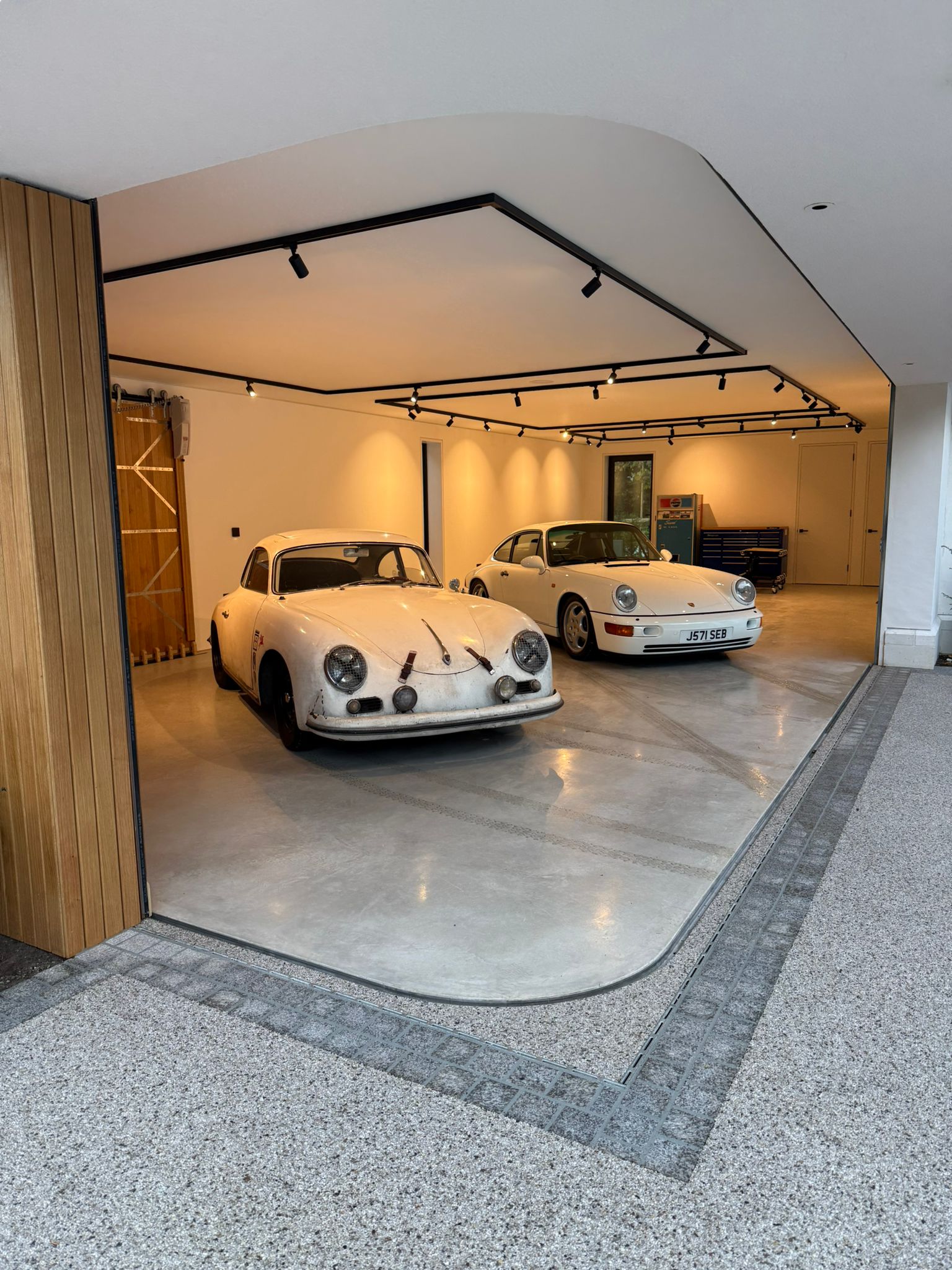 Two white Porsches, a classic 356 and a 964, in a modern Gulbarg garage.