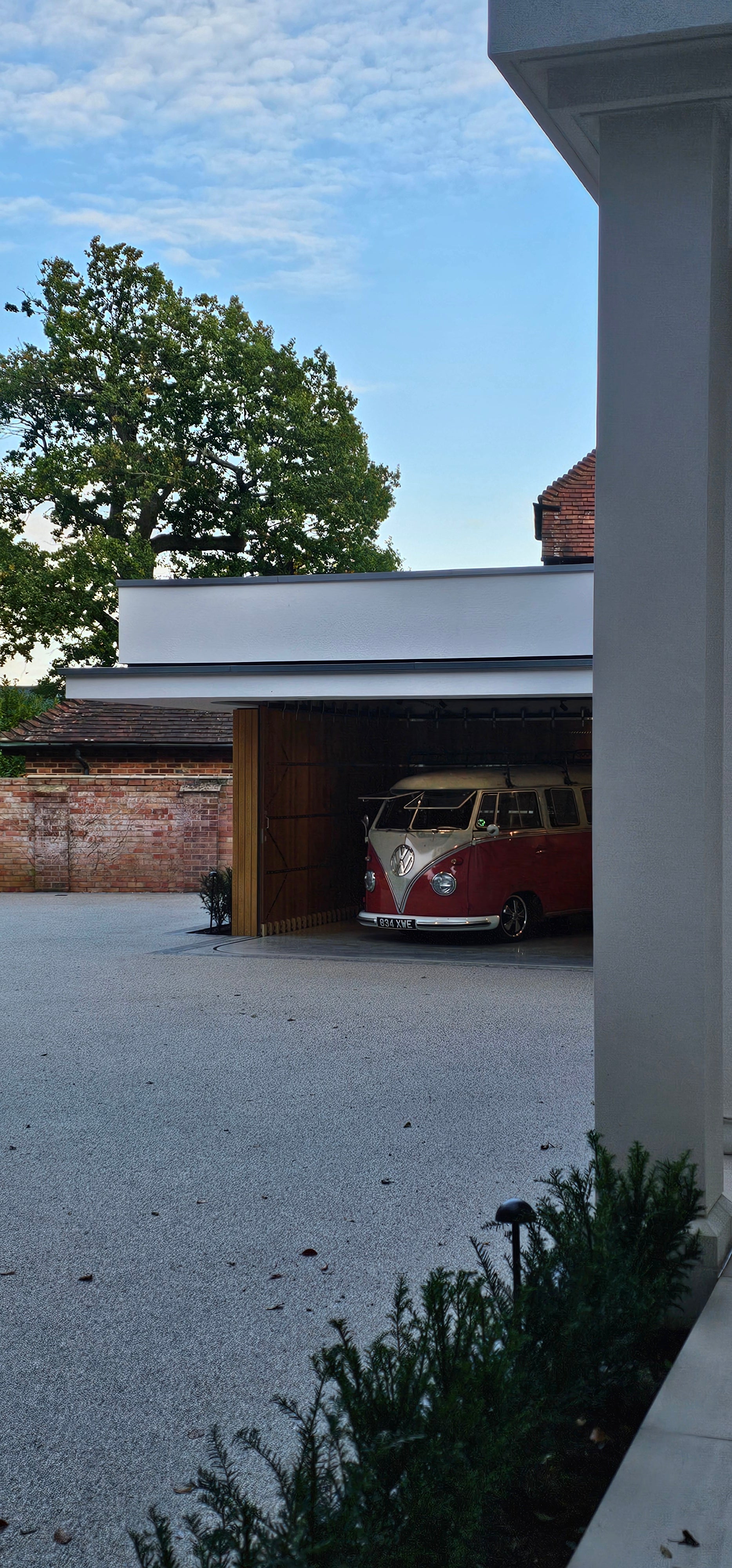Vintage red and white VW Type 2 bus parked inside a modern garage at Gulbarg, West Berkshire.