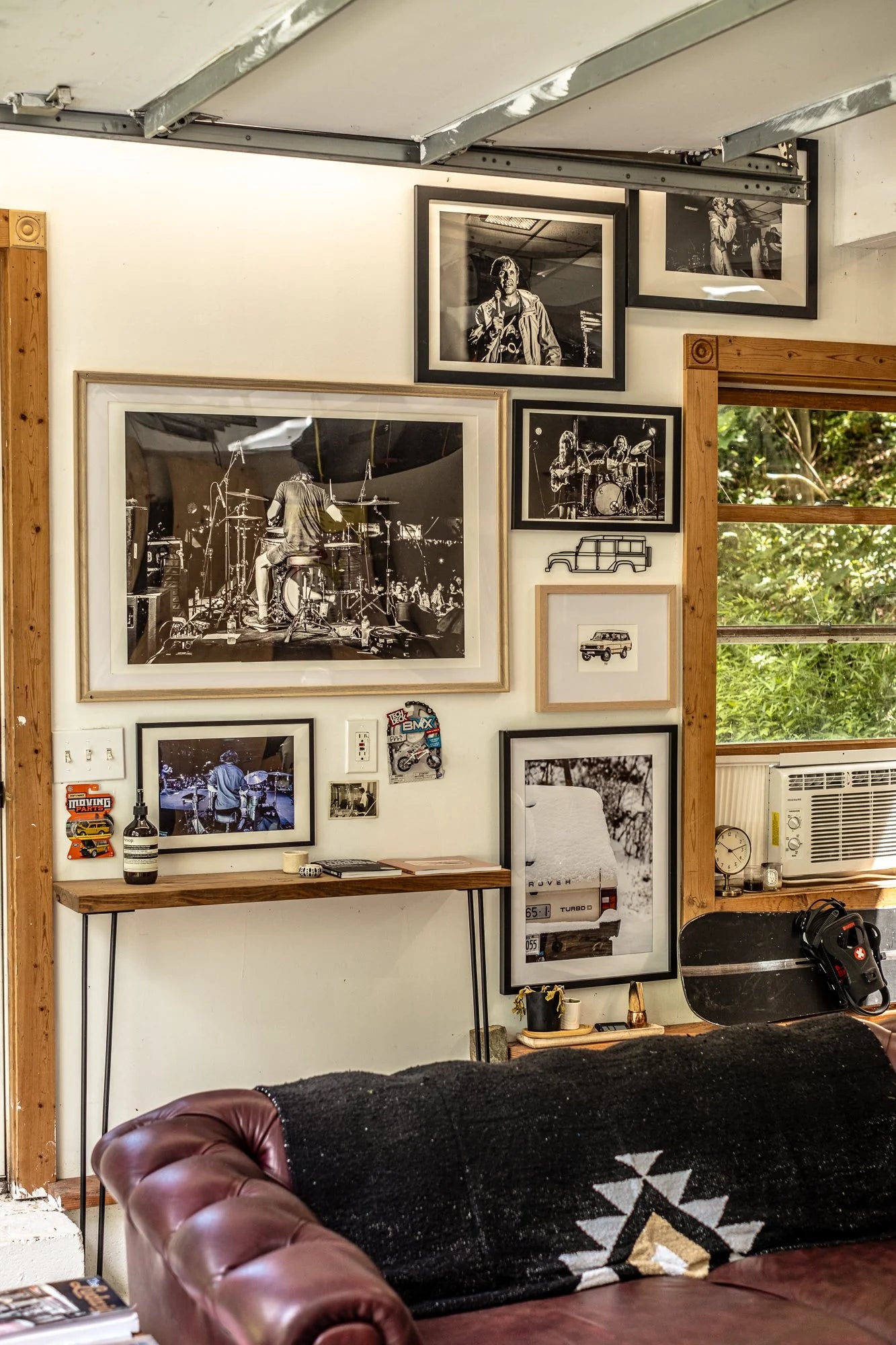 Eclectic gallery wall in a Hudson Valley garage living room with framed music and car art.