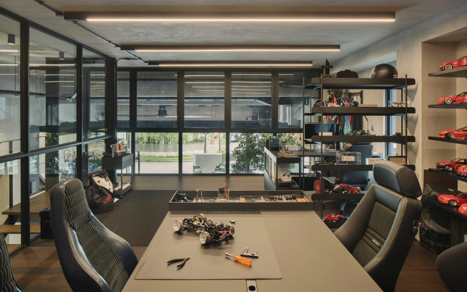 Modern garage house hobby workshop interior with workbench, RC car, tools, model cars, and Recaro seats.
