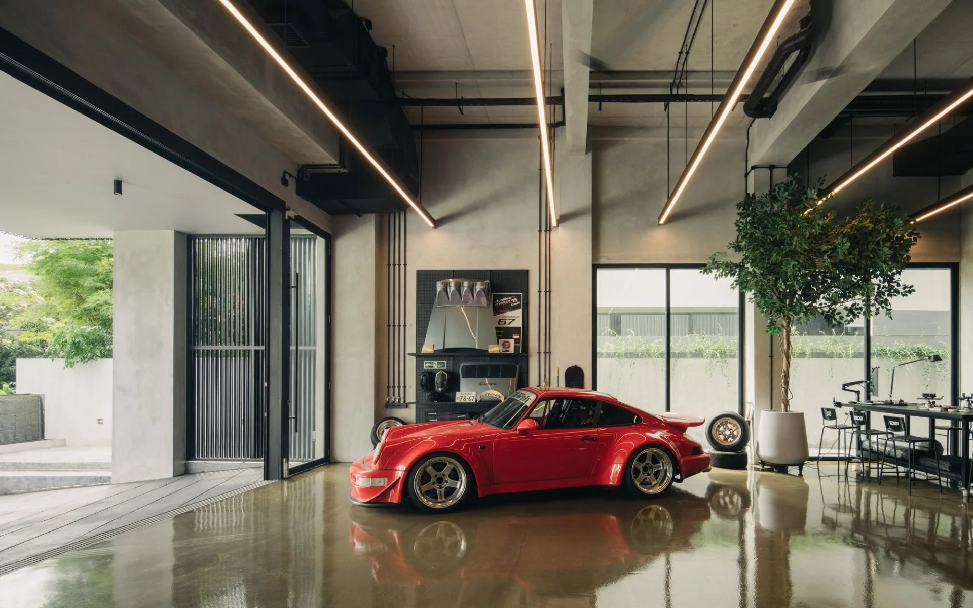 Red Porsche 911 in a modern industrial garage house interior with polished concrete floors and linear lighting.