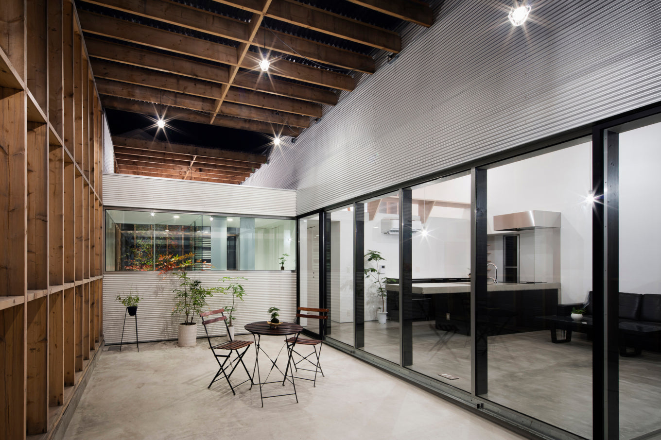 Modern outdoor patio of a Garage Terrace House in Kizugawa, Japan, with a bistro set and large windows.