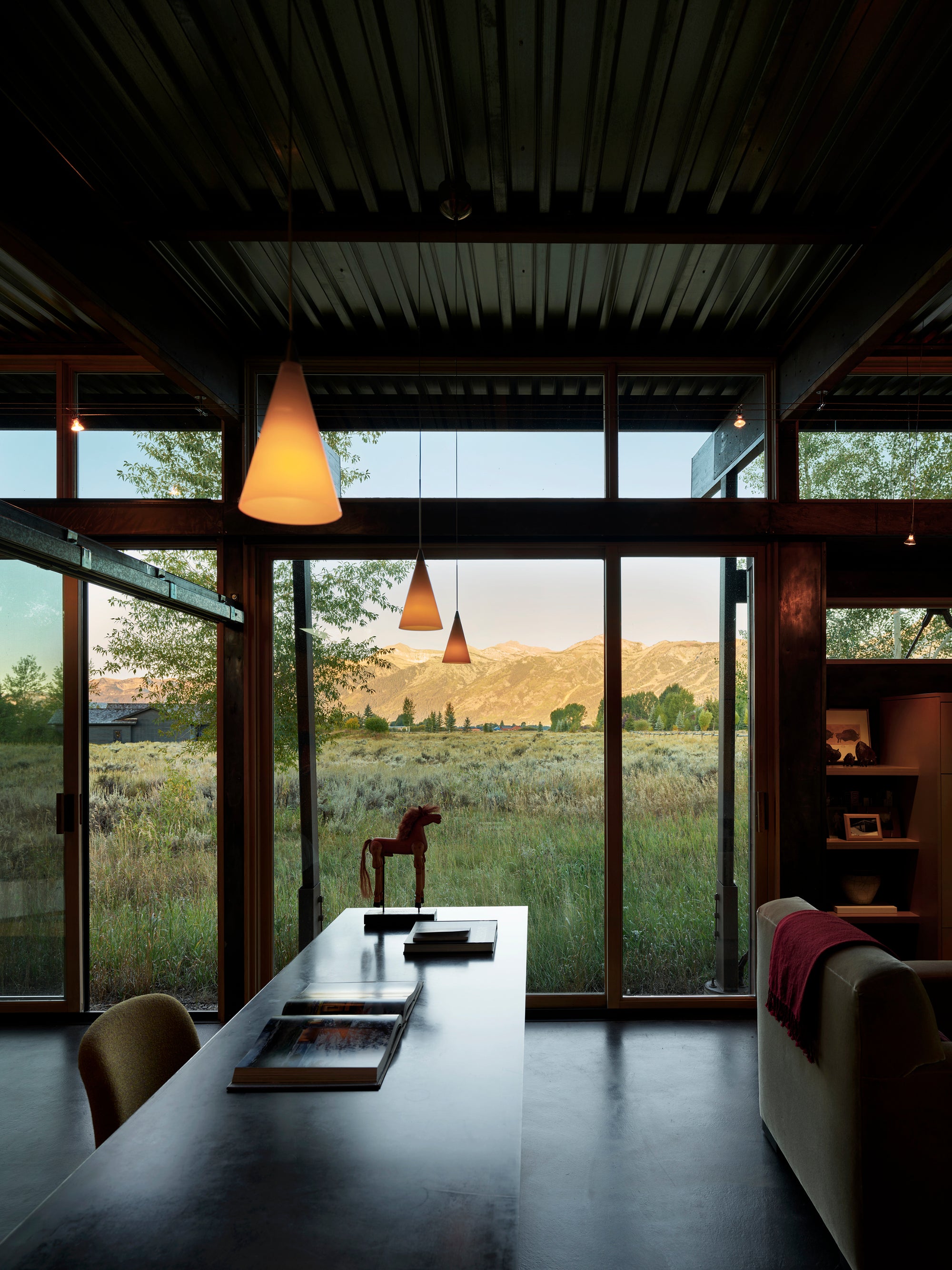 Modern Logan Pavilion interior in Jackson, WY, with floor-to-ceiling windows overlooking mountains.