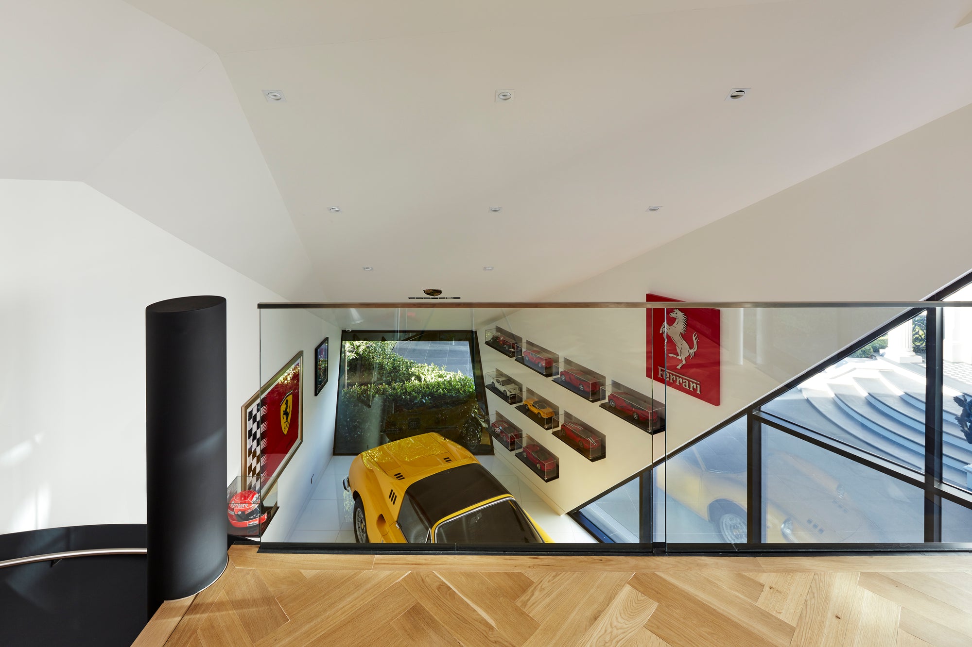 Modern luxury garage interior loft overlooking a yellow Ferrari Dino and Ferrari memorabilia on walls