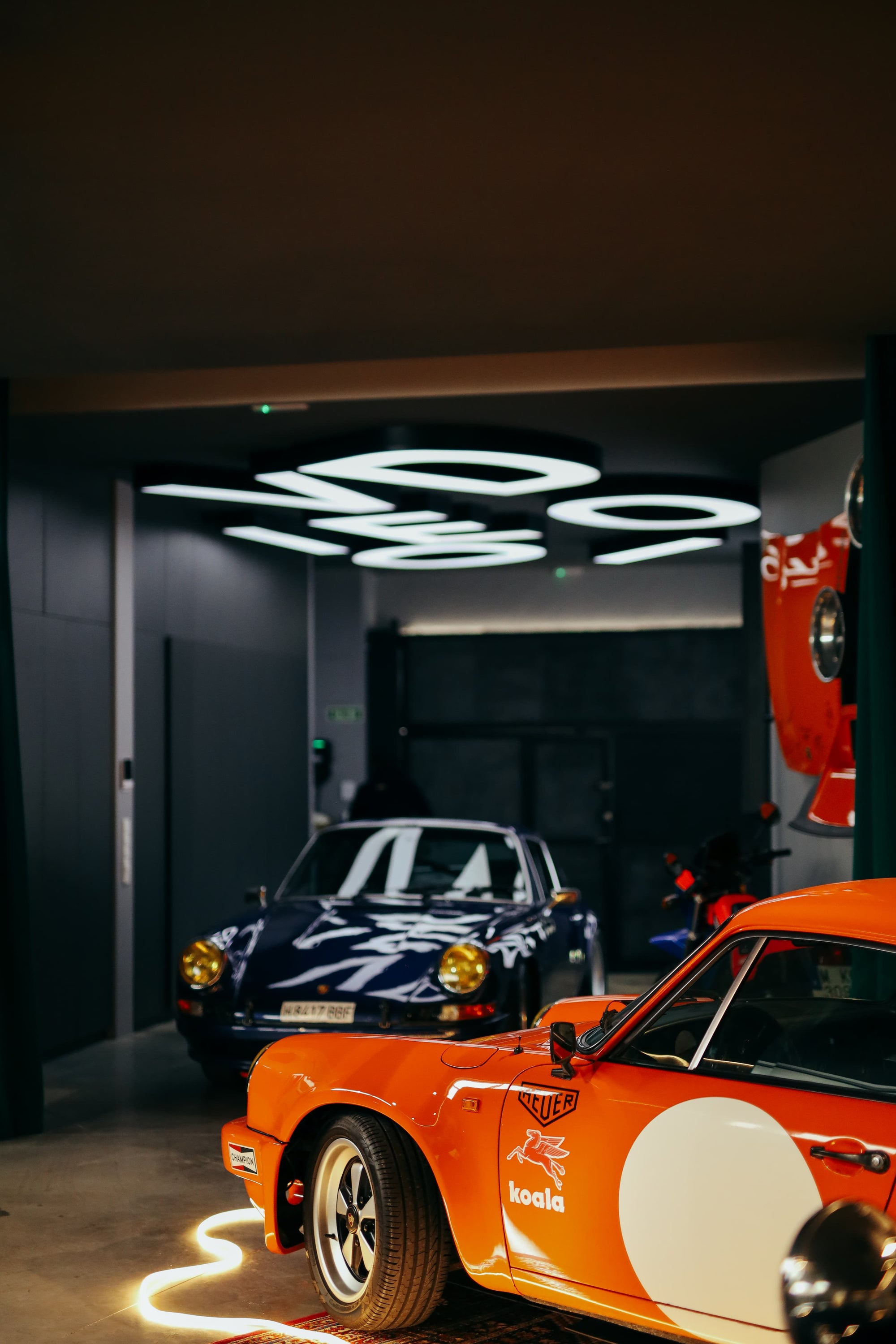 Orange and blue classic Porsche cars parked in Manu Campa's art studio garage in Madrid.