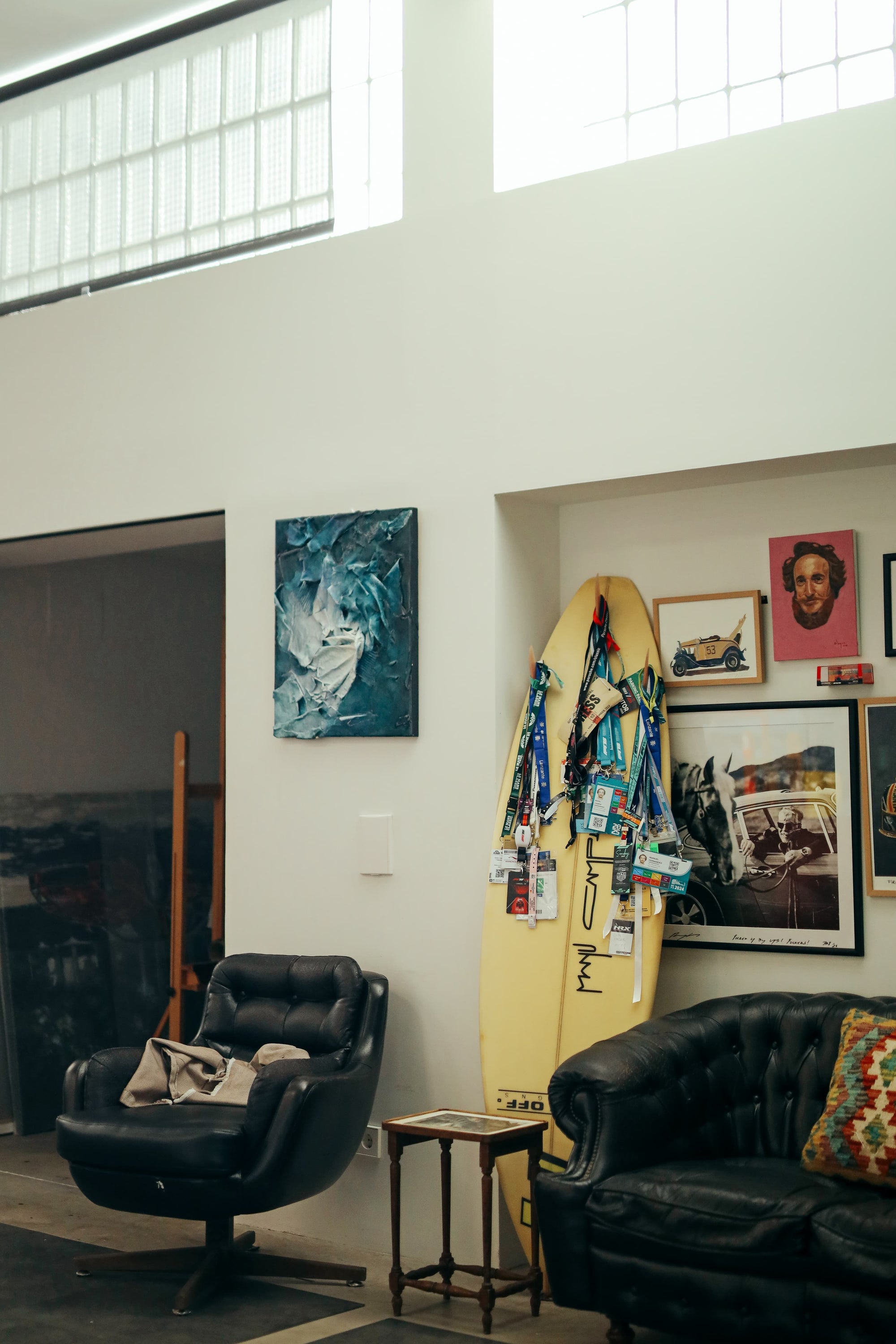 Eclectic lounge area in Manu Campa's garage studio with surfboard, leather seating, and artwork.