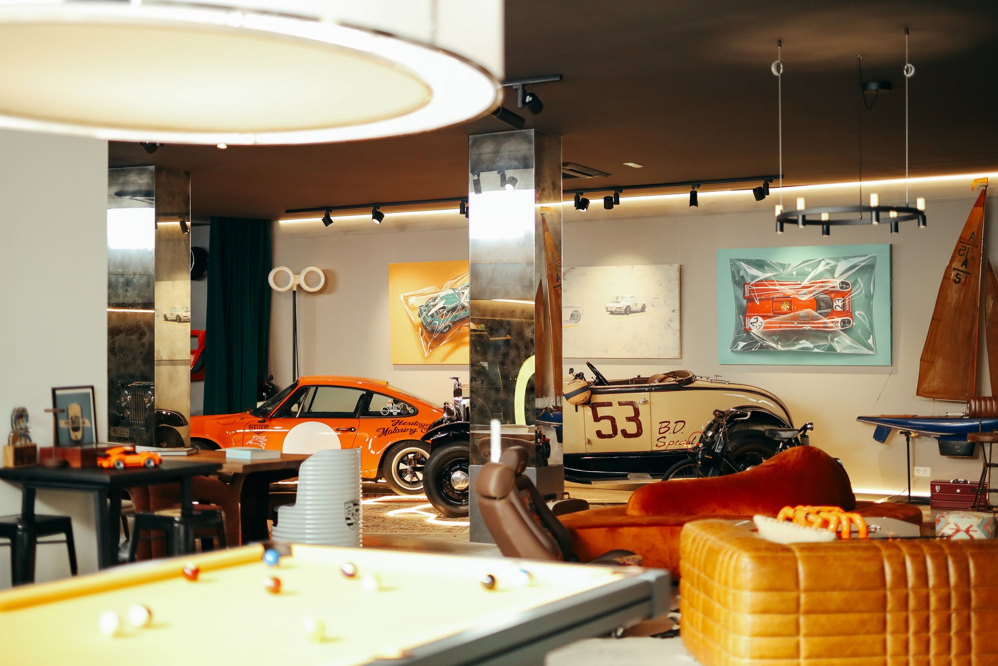Interior of Manu Campa's garage studio featuring vintage orange Porsche, classic roadster, art, and pool table.