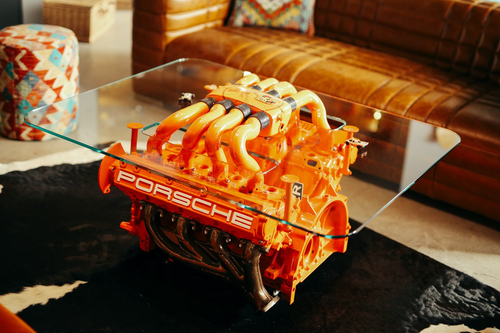 Custom orange Porsche engine coffee table with glass top in Manu Campa's garage studio.