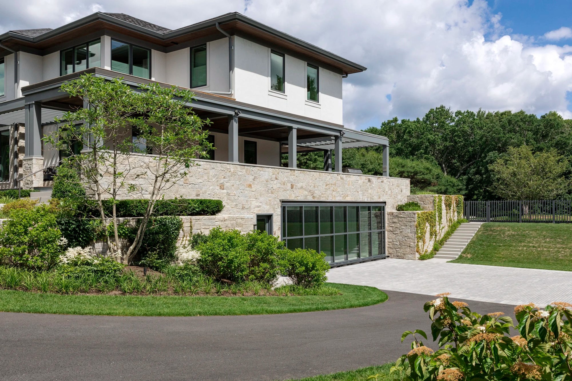 Modern house with stone facade and greenery in a Boston suburban area. 