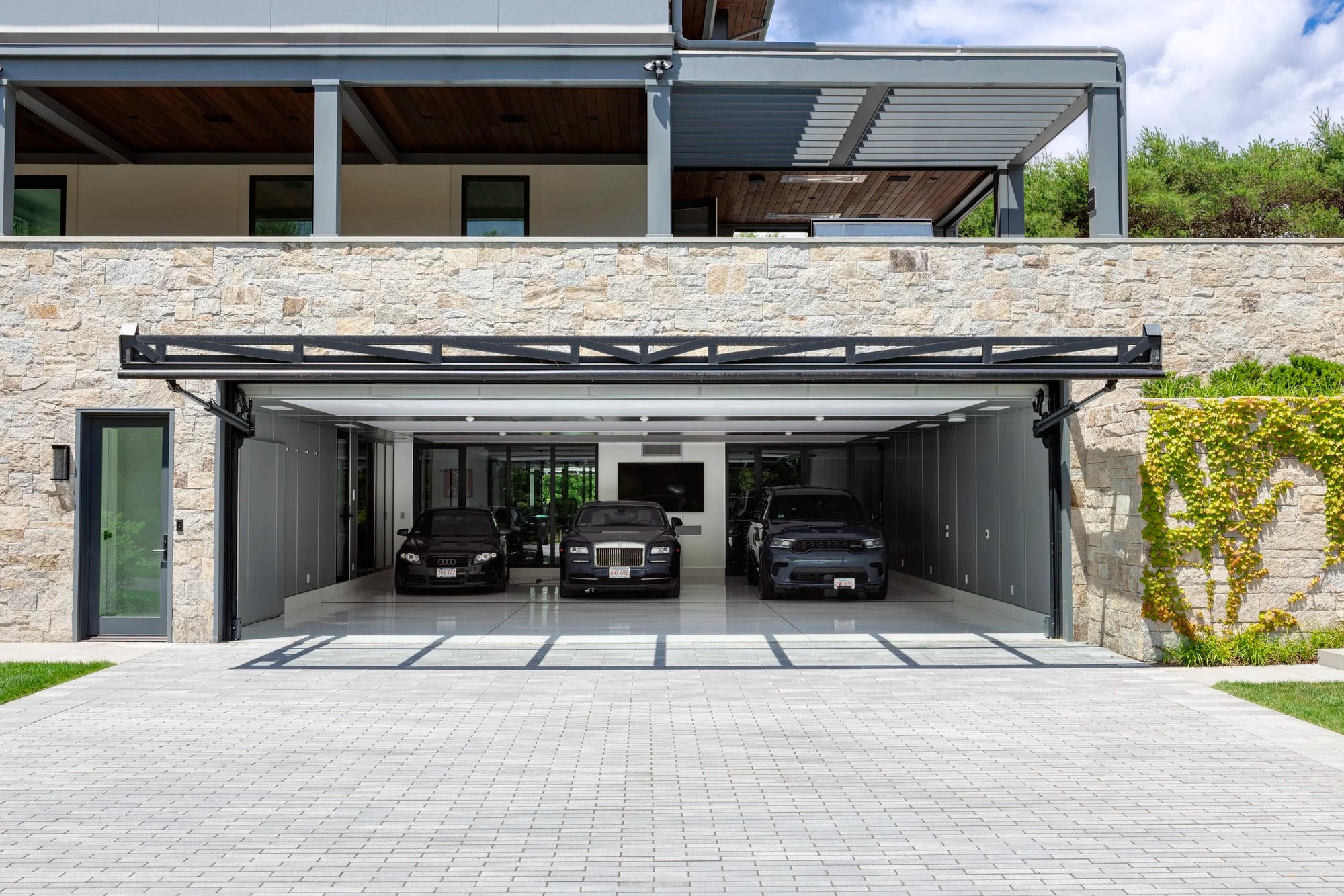 Modern house with a garage featuring a retractable glass door for exotic car collection.