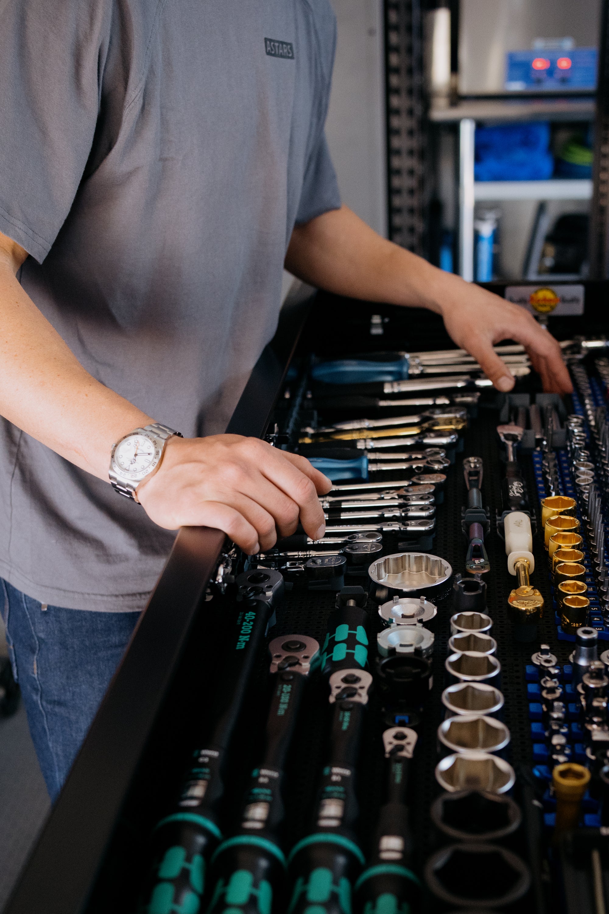Aaron Colton wearing a Rolex Explorer on his wrist organizing tools in a drawer with a focus on a toolbox filled with organized tools 