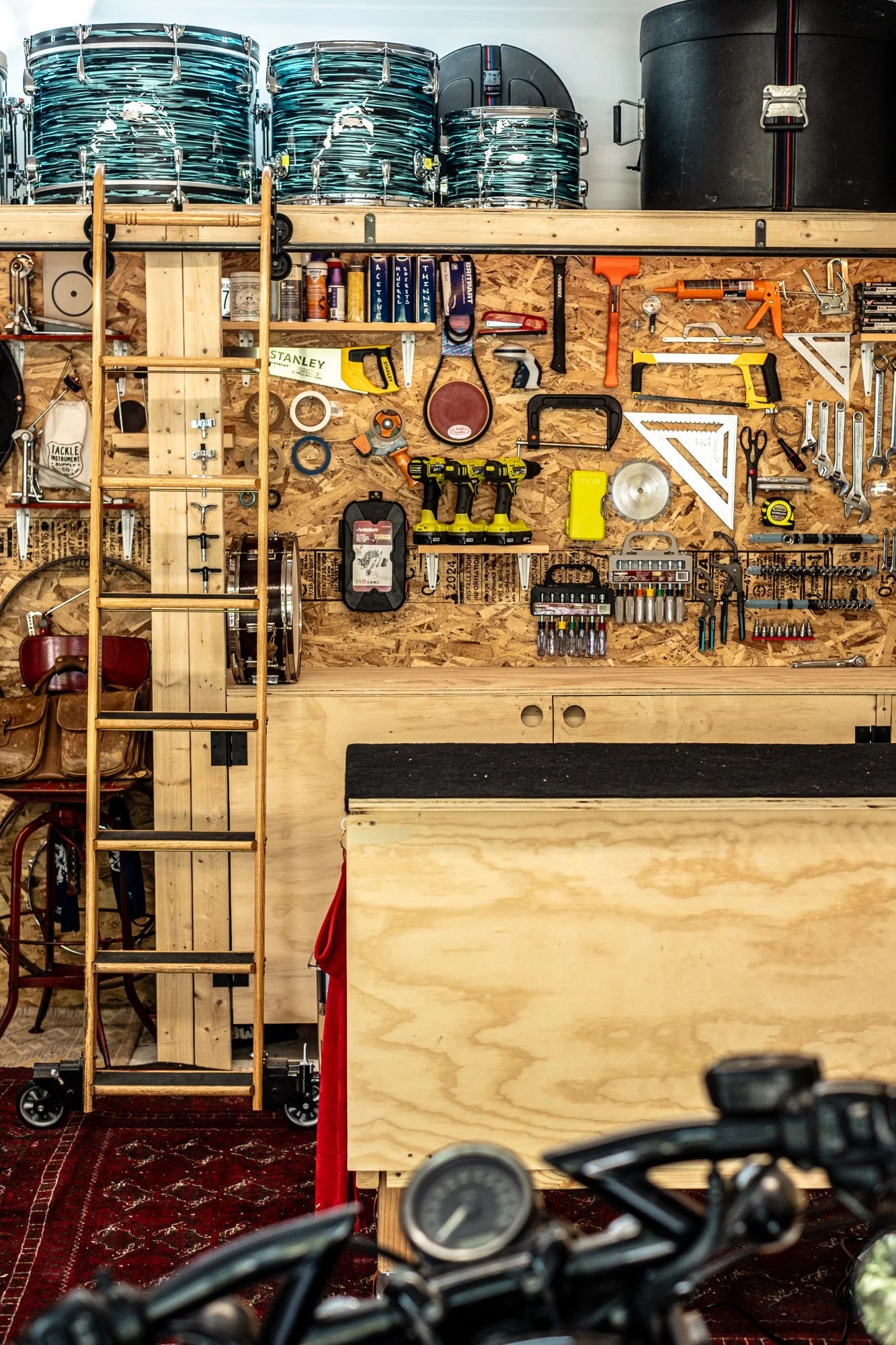 Wall-mounted tool bench with various tools and equipment in a garage workshop setting.
