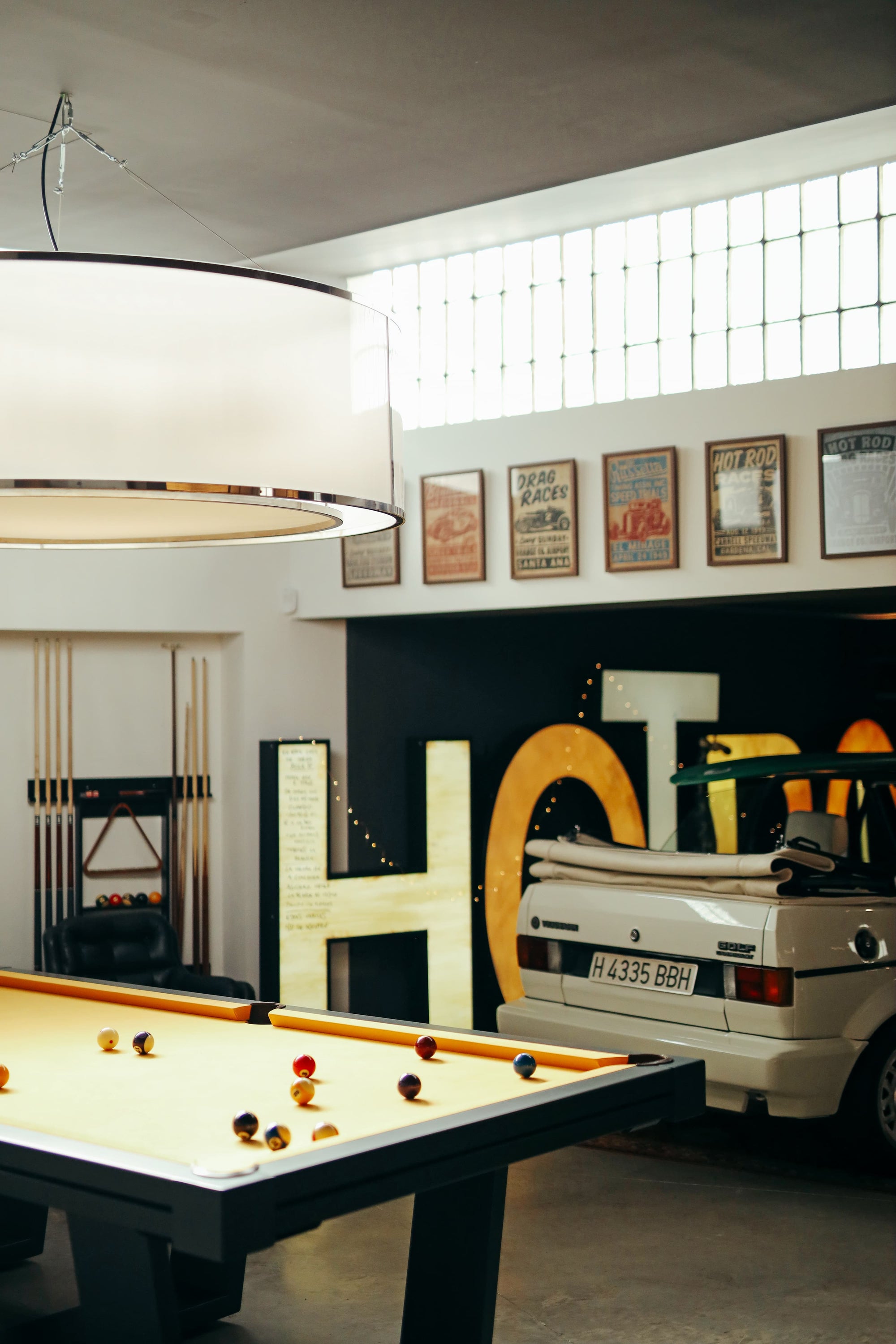 Garage game room with pool table, vintage VW car, and wall decorations.