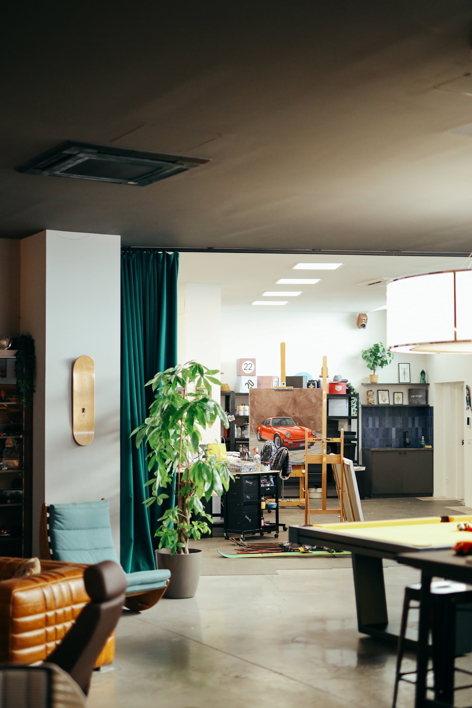 Interior view of Manu Campa's garage studio with Porsche painting, pool table, and lounge area.