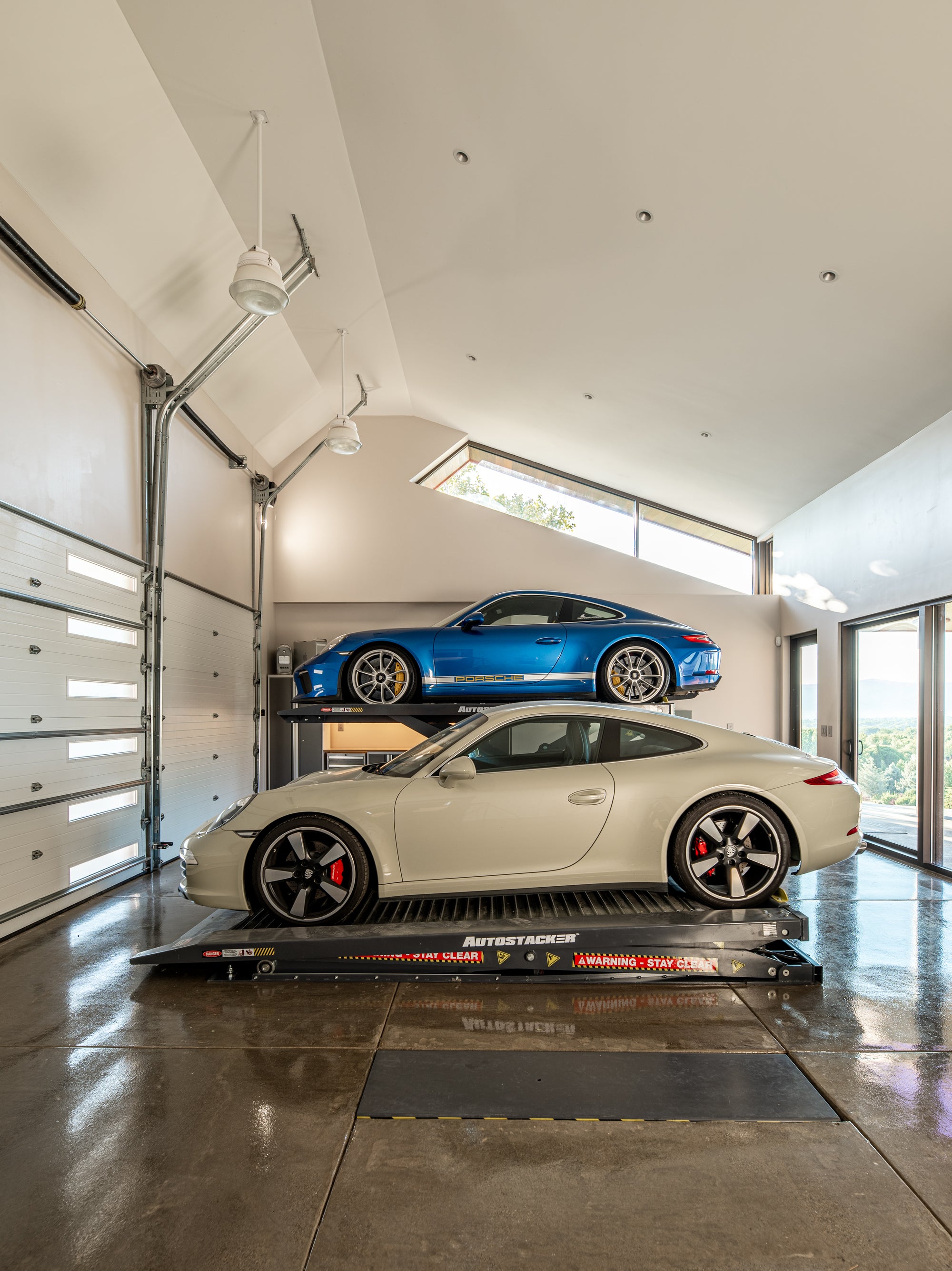 Porsche garage with BendPak AutoStacker lift storing two cars with full access and polished concrete floors