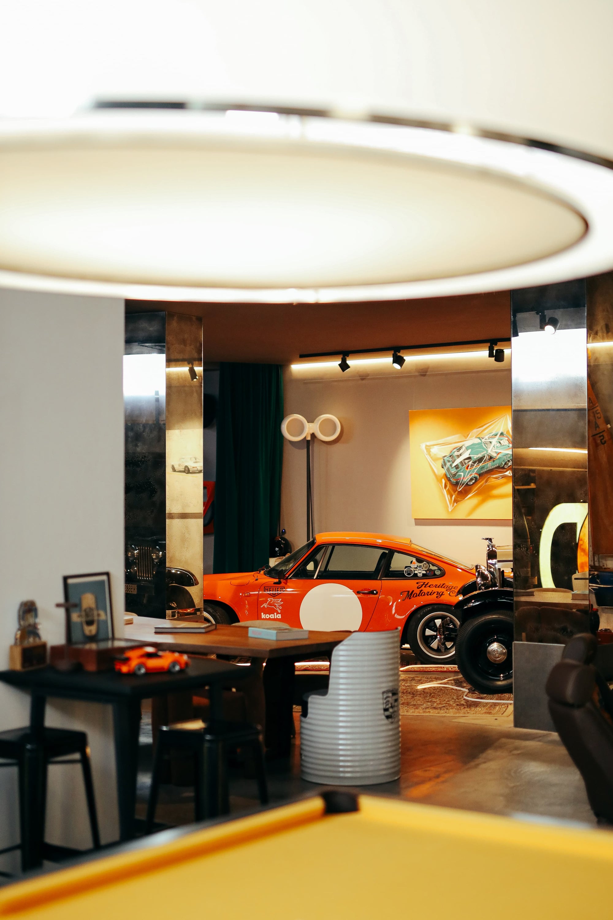 Interior view of Manu Campa's Madrid-based garage studio featuring an orange Porsche 911 race car and art.