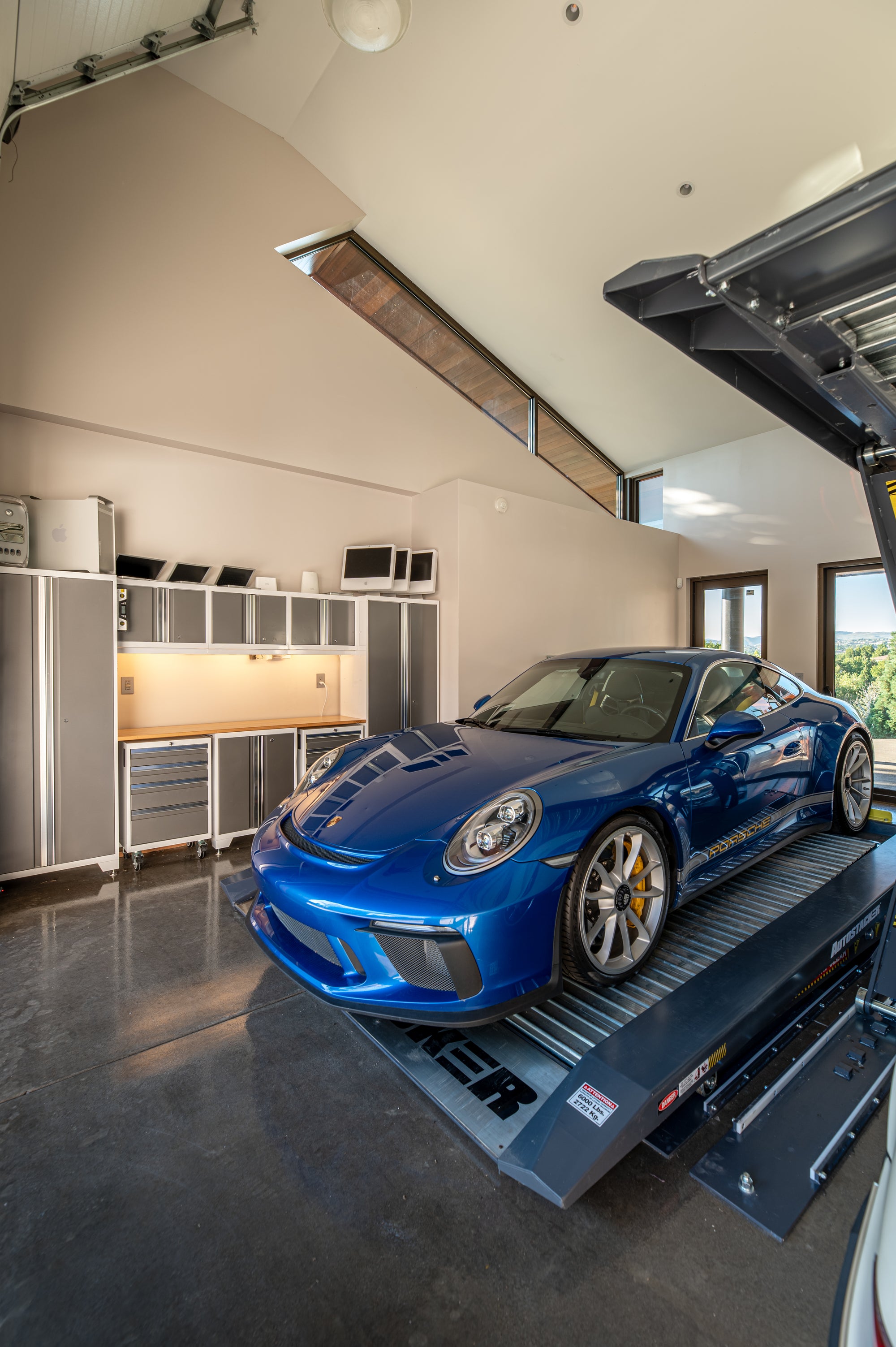 Porsche garage workshop with storage cabinets and car lift designed for maintenance and tuning