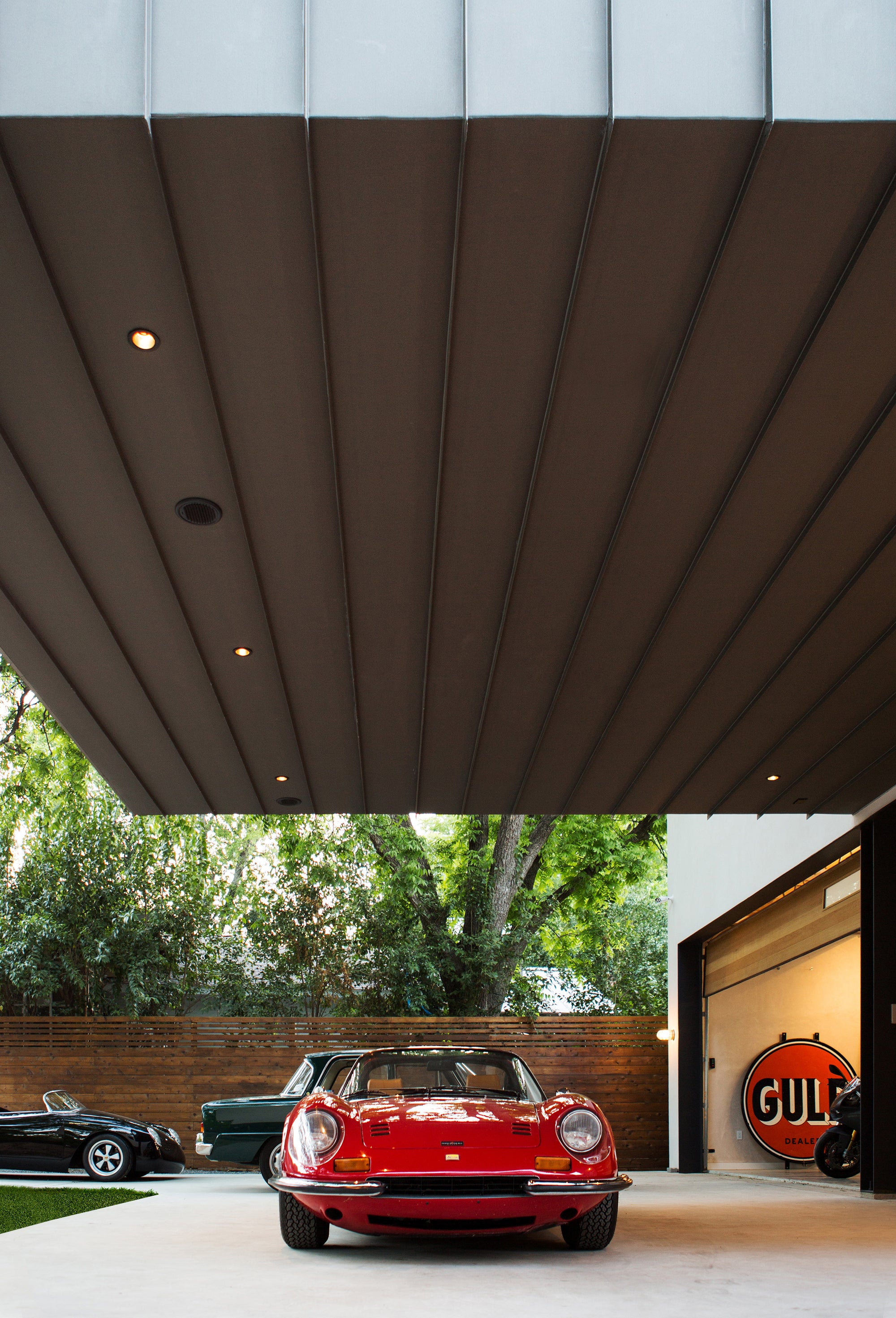 Red Ferrari Dino 246 GT parked under a modern architectural overhang at Autohaus in Austin, TX.