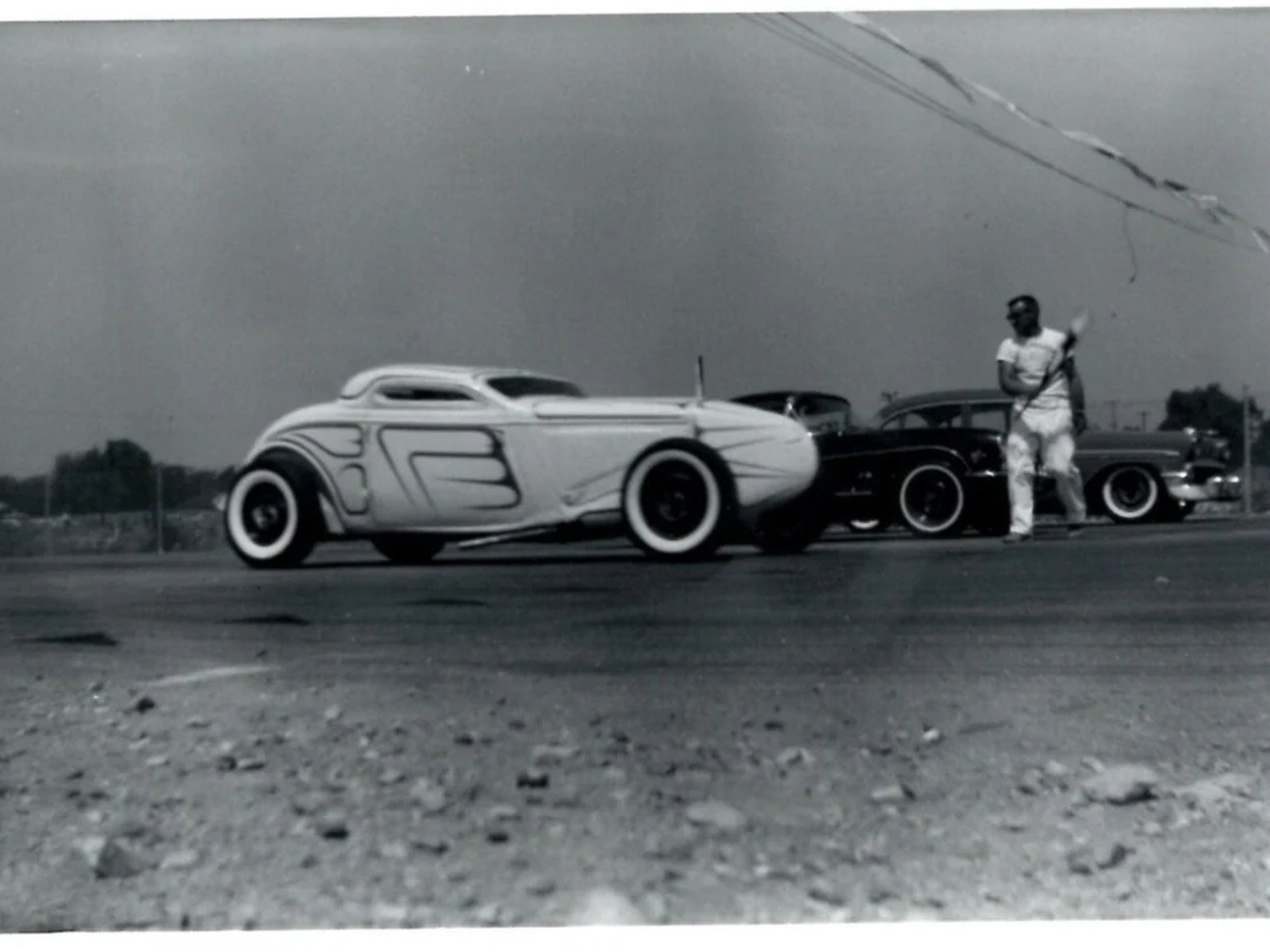 Vintage black and white photo of hot rod enthusiasts with custom cars in Northern California.