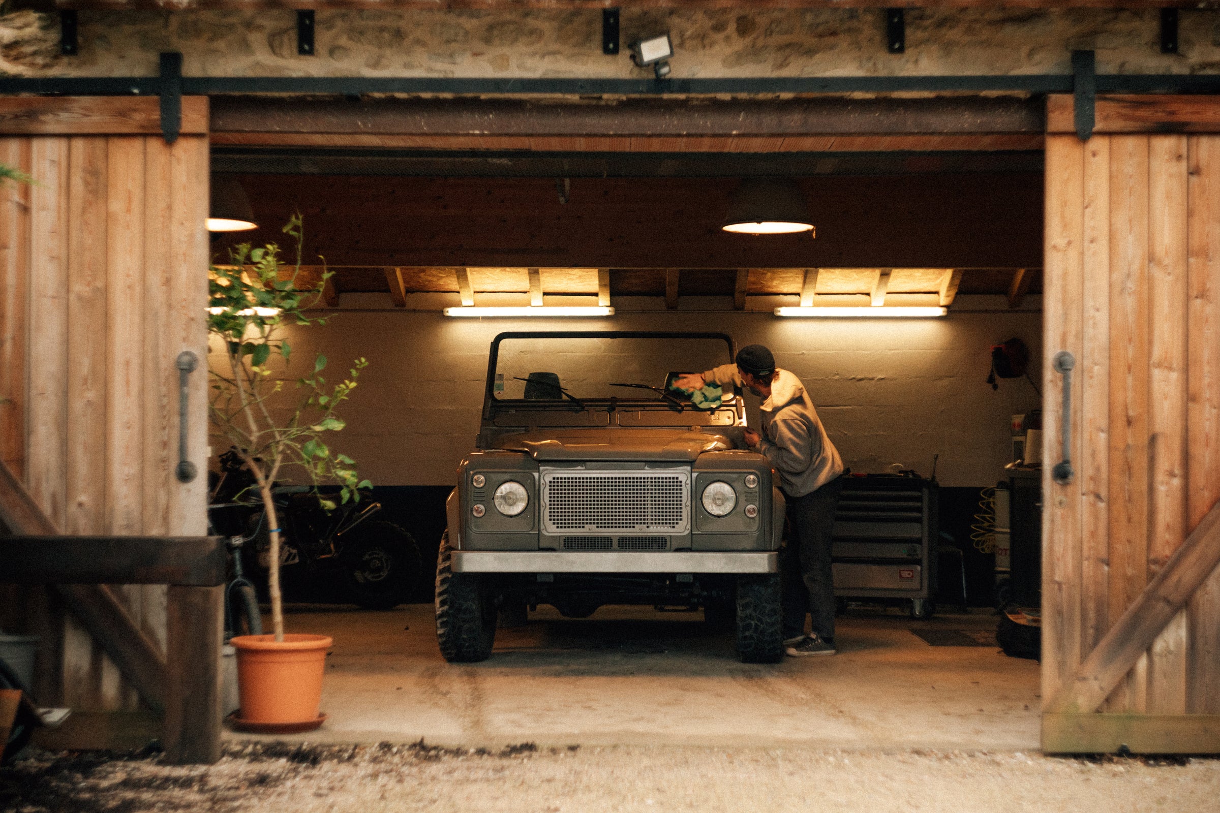 Restored Land Rover Defender framed by open wooden garage doors in southern France
