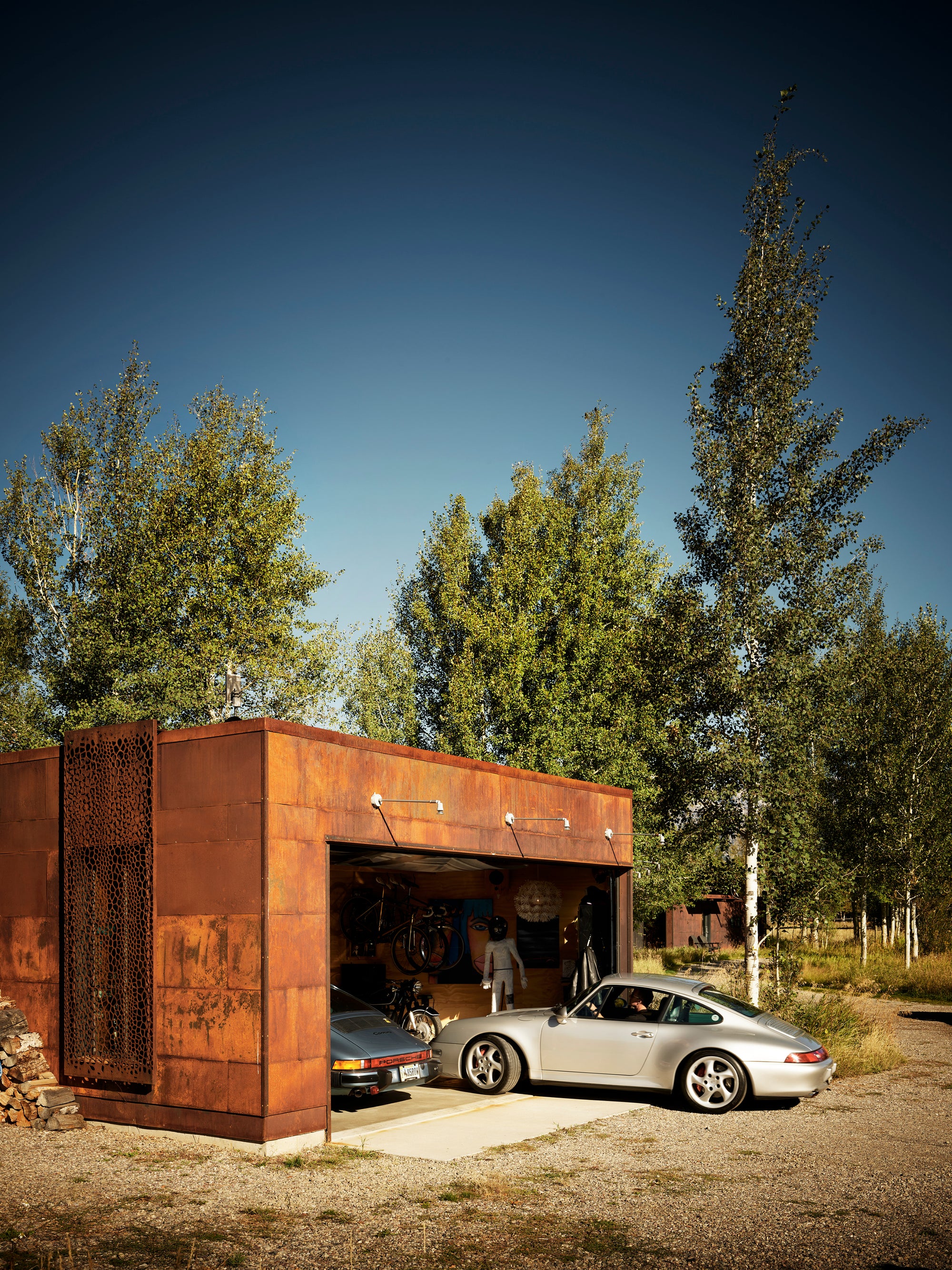 Silver Porsche 911 exiting a modern Corten steel garage at Logan Pavilion, Jackson, WY.