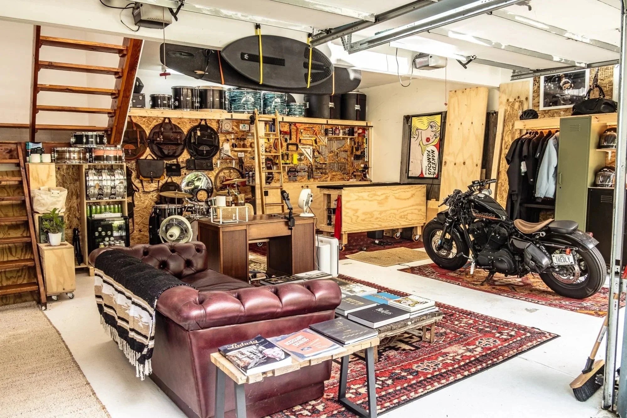 Spacious Hudson Valley garage workshop with motorcycle, drums, tools, leather couch, and surfboards.