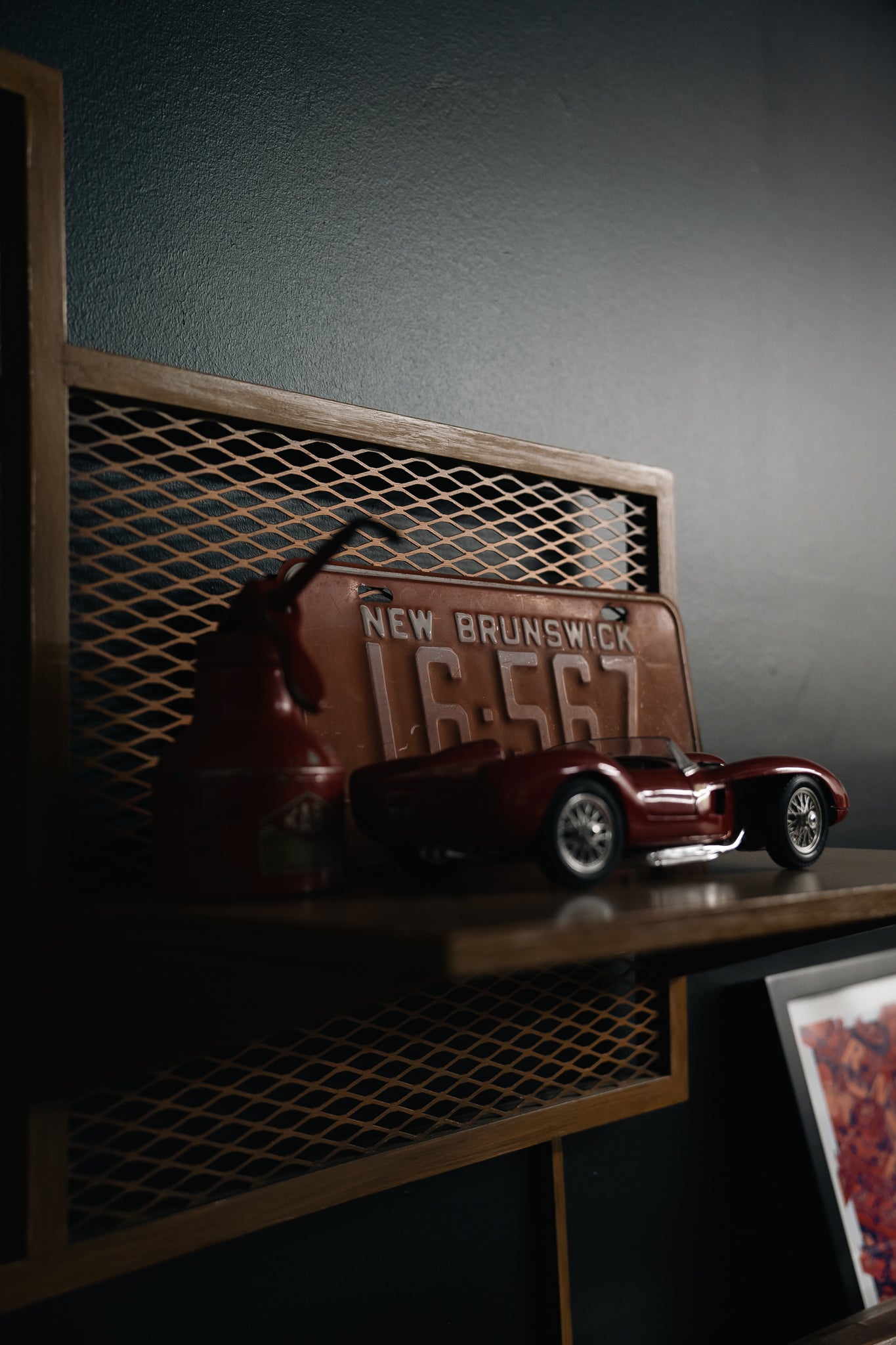 Vintage automotive decor, vintage license plate, and die-cast model car displayed on shelving inside enthusiast garage