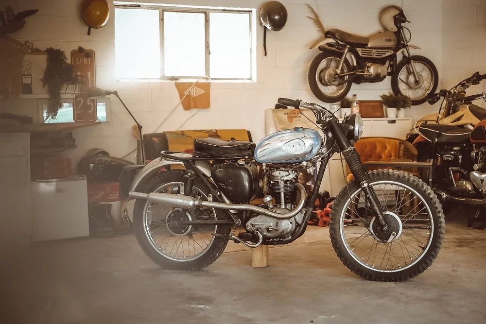 Vintage motorcycle on display in a garage with other motorcycles and equipment.