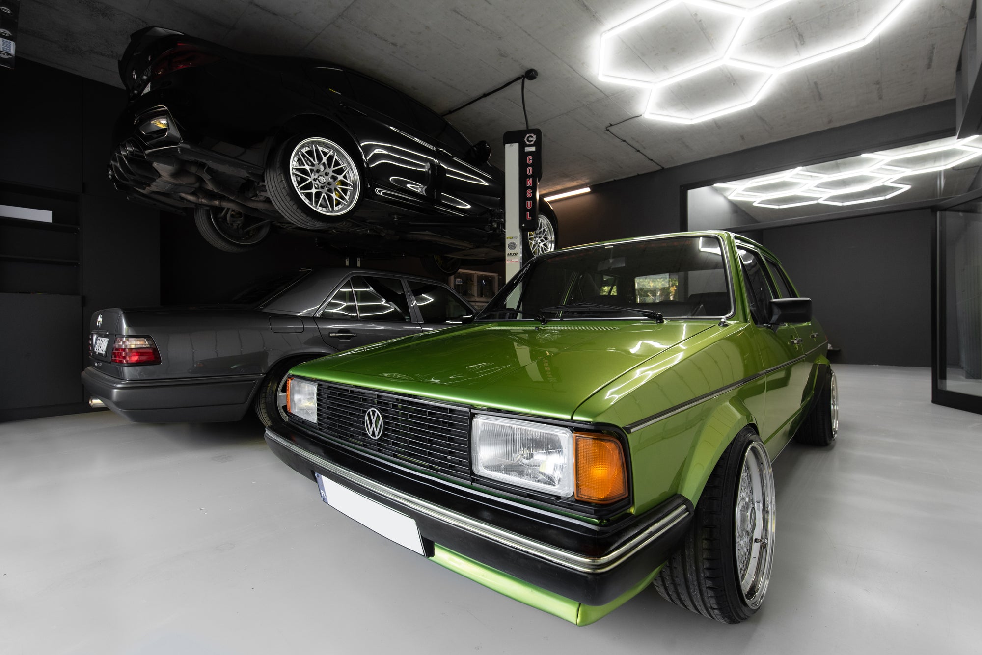 Volkswagen Golf in modern garage with BMW on lift and hex LED ceiling lighting