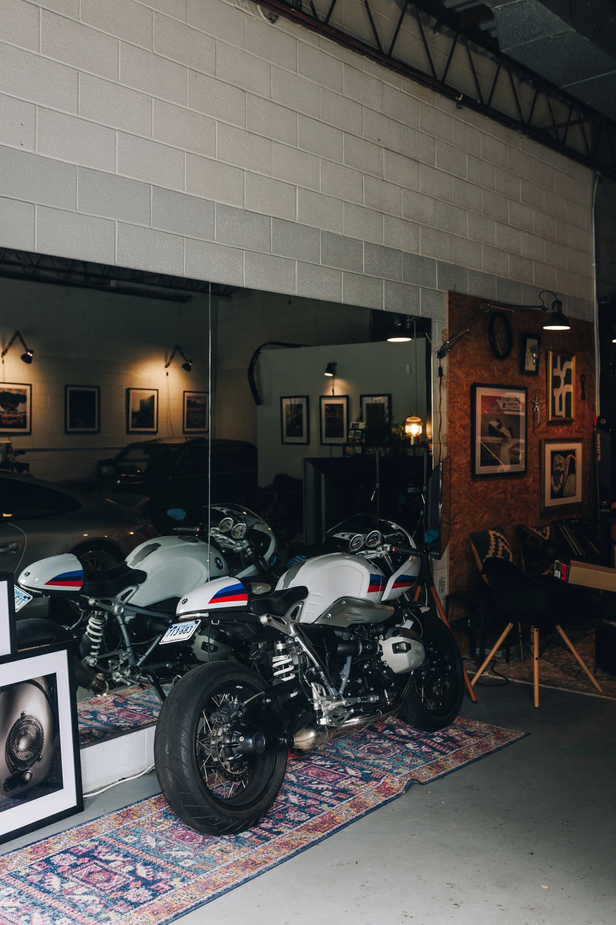 BMW motorcycles on display in a garage with framed pictures on the wall.