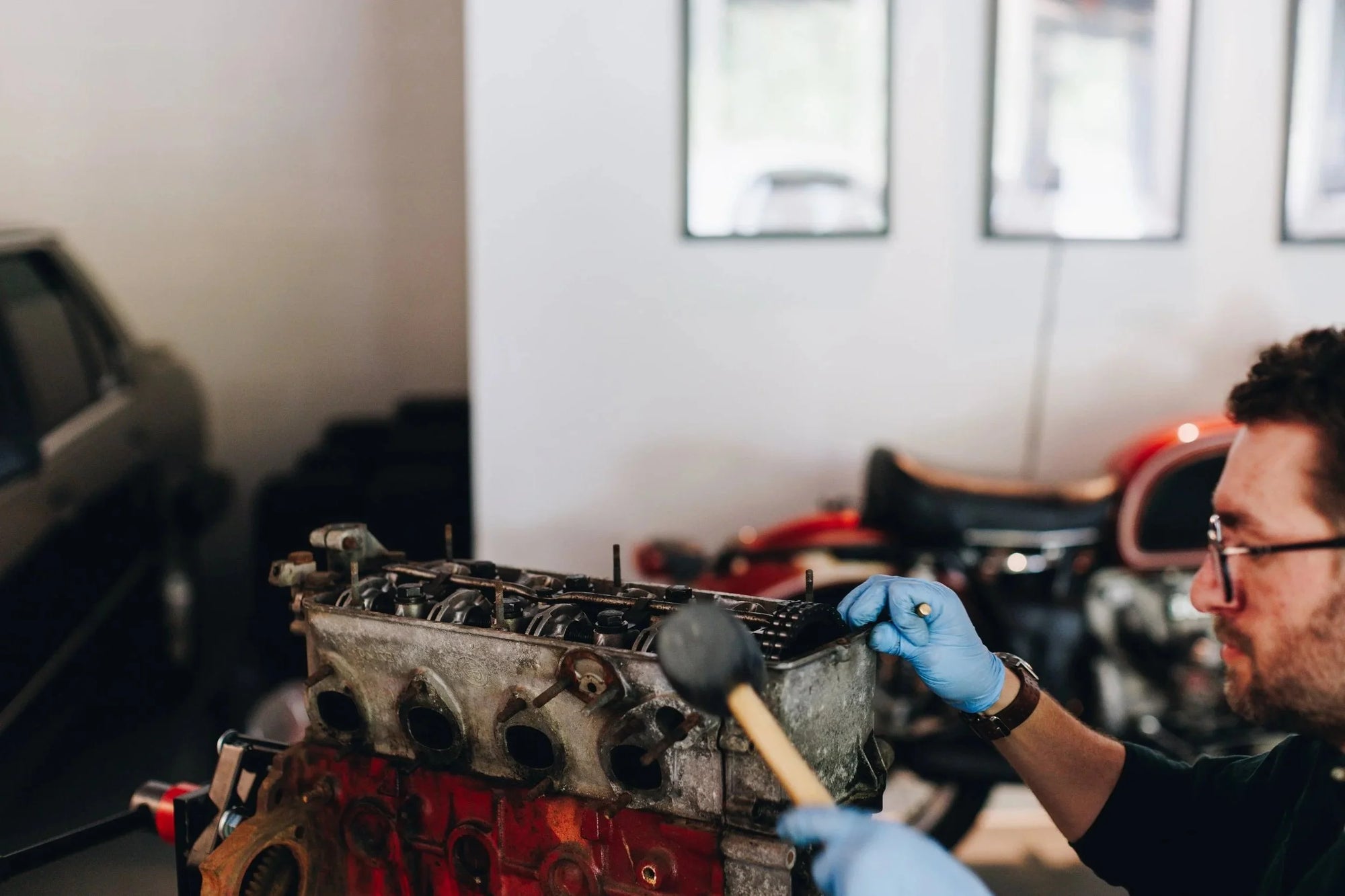 Person working on a car engine in a garage setting