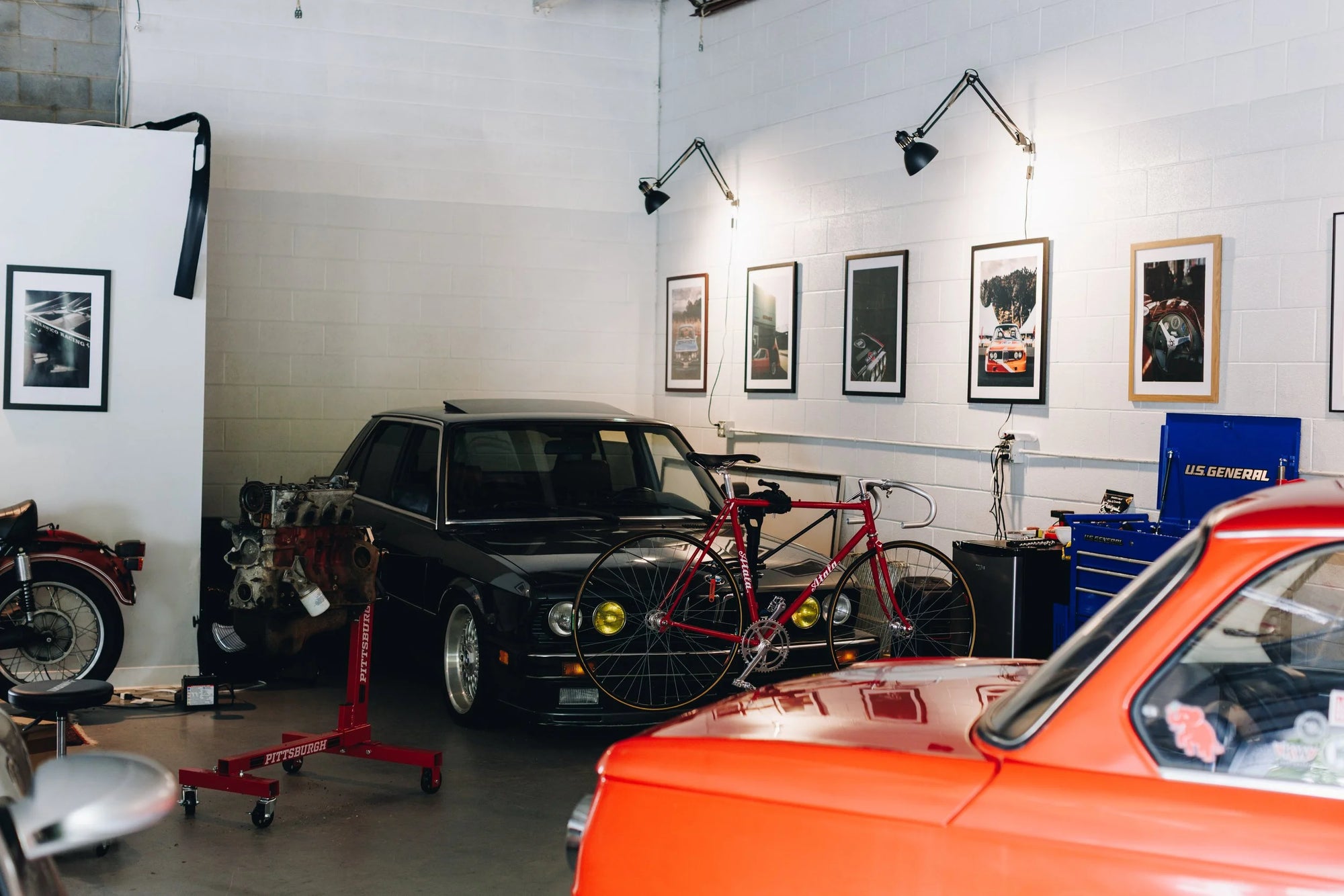Garage with cars, vintage BMW, a bicycle, and various tools on shelves.